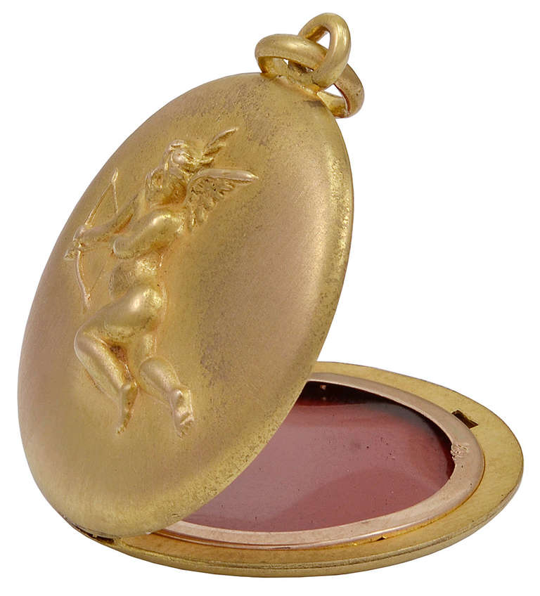Antique 14K gold round locket. Matte gold finish with applied flying cupid, bearing bow and arrow. Opens to reveal two bezels which hold two pictures.
Keep this close to your heart.