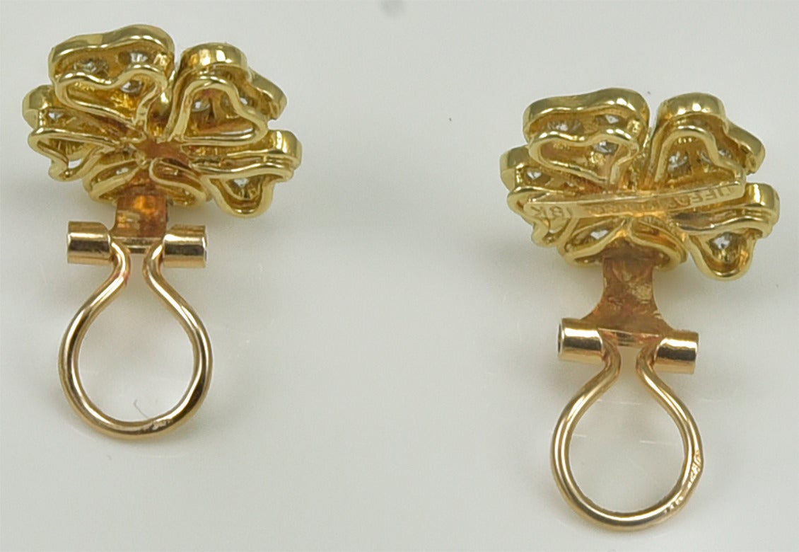 Bright five-leaf clover earrings, made and signed by TIFFANY & CO. 
18K yellow gold, set with diamonds and a center faceted emerald. 
1/2