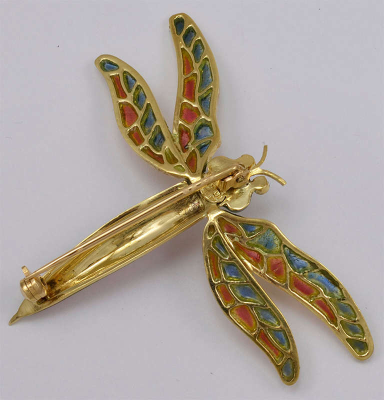 Exquisite 18K yellow gold and transparent enamel dragonfly pin. Head and body are vibrant emerald green and orange enamel. When the pin is held to the light, the wings look like blue and rose stained glass. 

Perfect and beautiful.