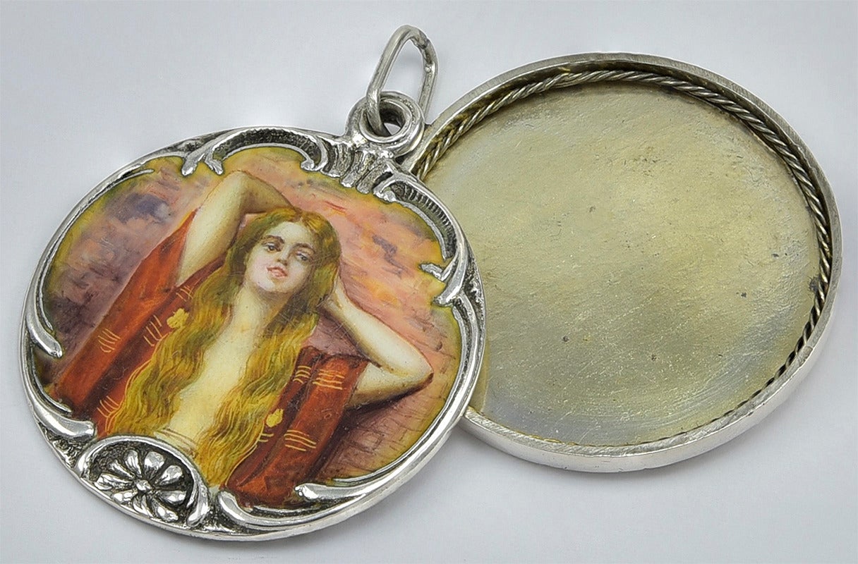Beautiful art nouveau slide locket.  Lovely enamel locket, depicting a woman with flowing hair, dressed in a silk robe.  Embossed and applied silver rim surrounds the enamel (.800 silver). 1 1/4