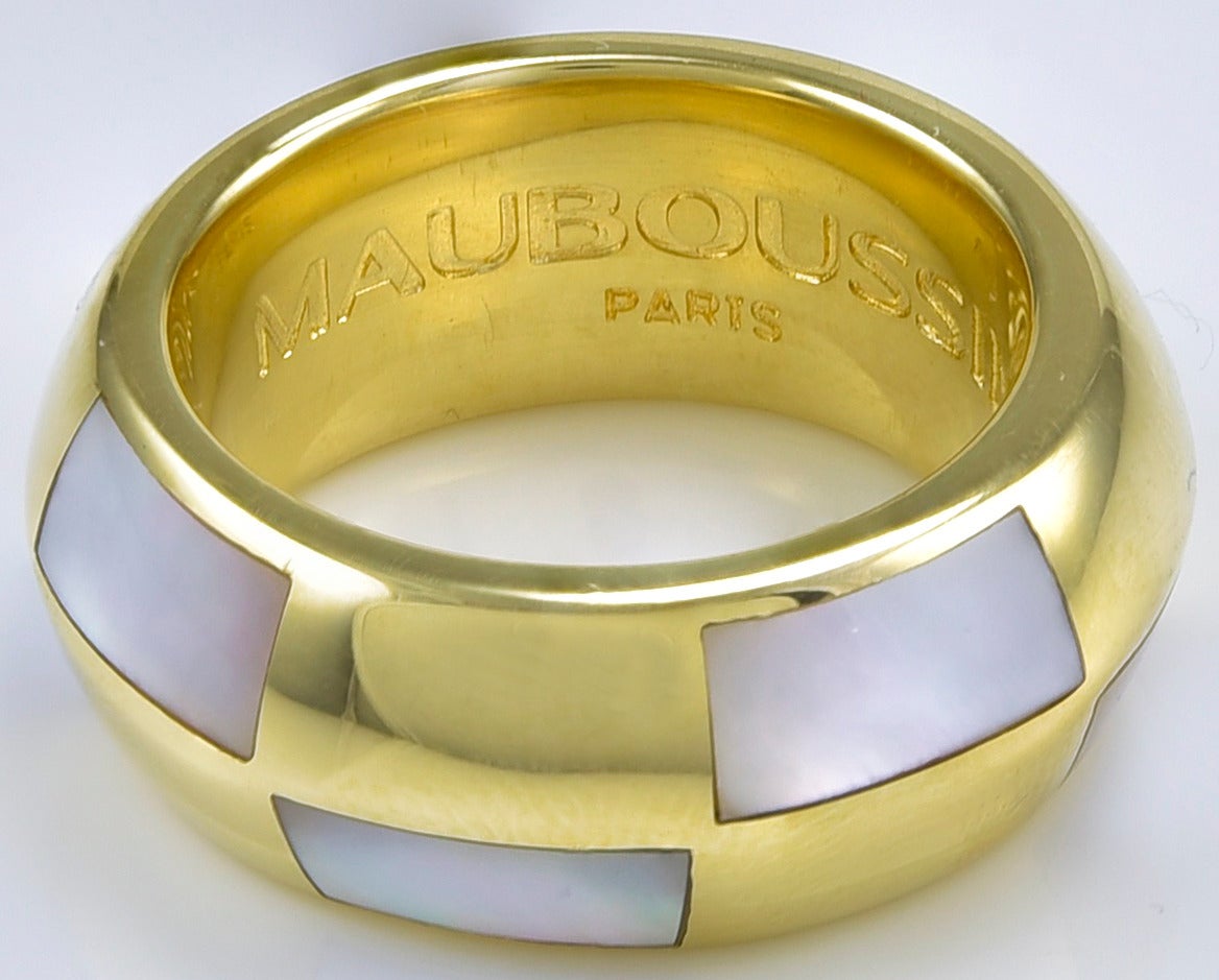 Belle bague en or jaune 18K, réalisée et signée par MAUBOUSSIN PARIS.  Avec de la nacre blanche incrustée dans un motif géométrique.  L'anneau est biseauté, pour souligner son aspect linéaire.  Taille 6 1/4.  Un bijou très original et