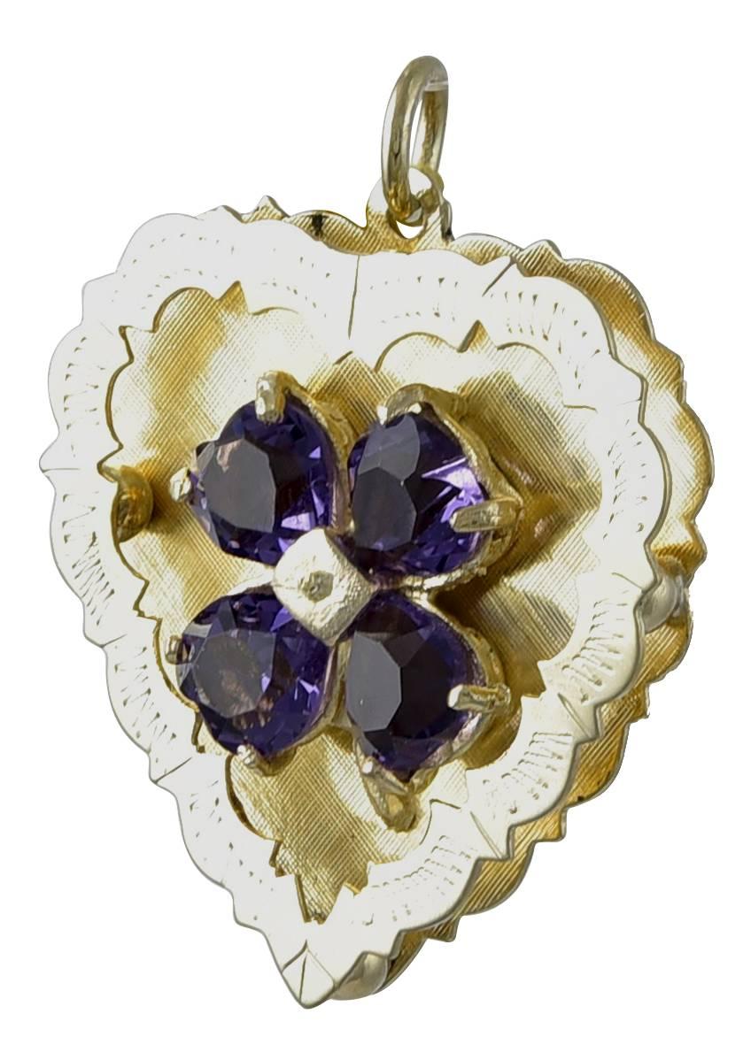 Beautiful figural heart charm. Textured 14K yellow gold background with a raised and engraved gallery. An applied four leaf clover in the center consists of four heart-shaped faceted amethysts. 1-1/8