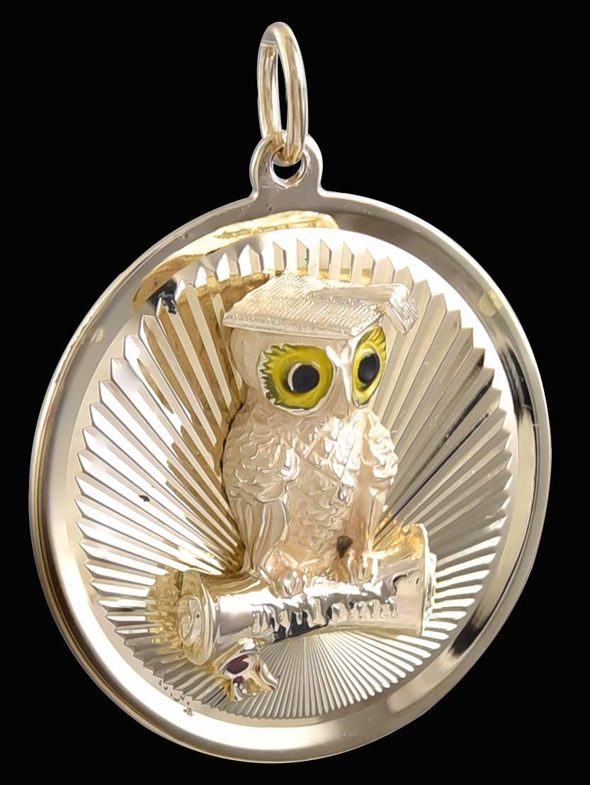 An appealing14K yellow gold graduation charm.  A figural owl is applied to a background of deep radiating lines.  The eyes are enameled.  He is wearing a mortar board and is perched on a 