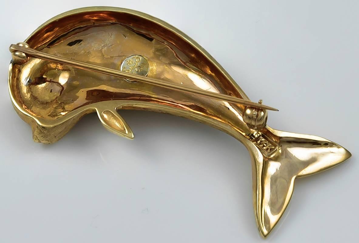 Figural dolphin pin.  14K textured yellow gold with a faceted ruby eye.  1 3/4