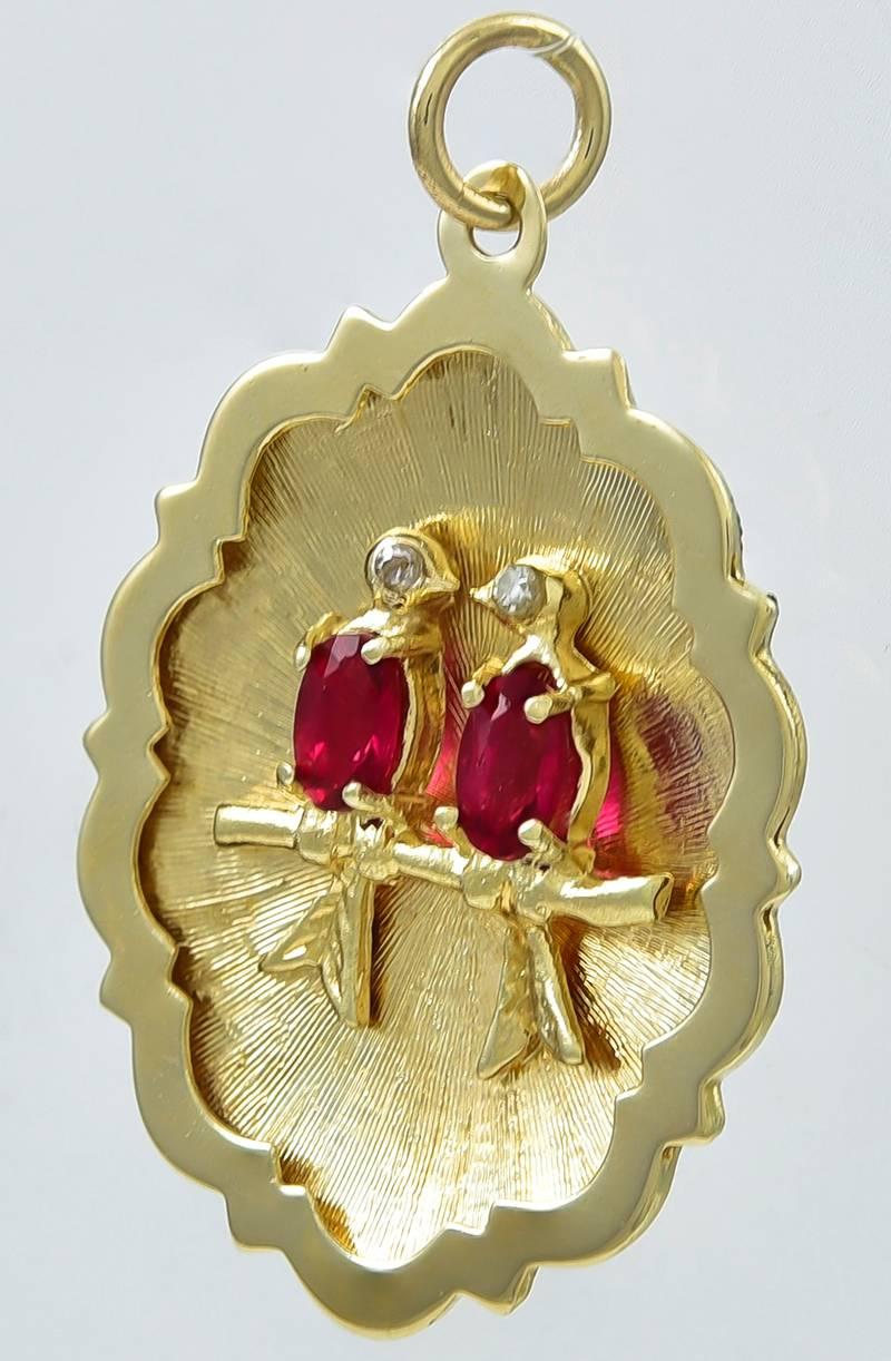 Figural  pair of lovebirds, facing each other, sitting on a branch.  14K textured gold, with shiny gold scalloped border.  The applied birds have tourmaline bodies and diamond eyes.  1 1/4