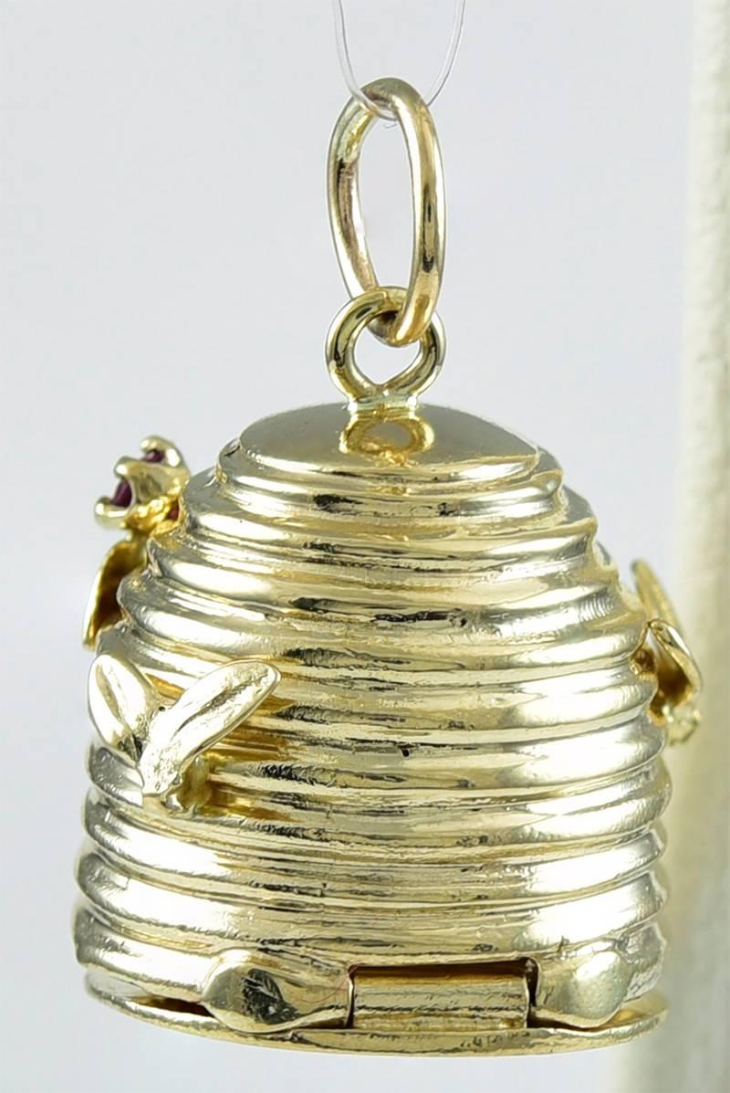 Figural beehive charm, with applied bees.  Heavy 14K yellow gold, set with  sapphire and a ruby.  Bottom of hive is hinged; it opens to reveal a cut-out message:  