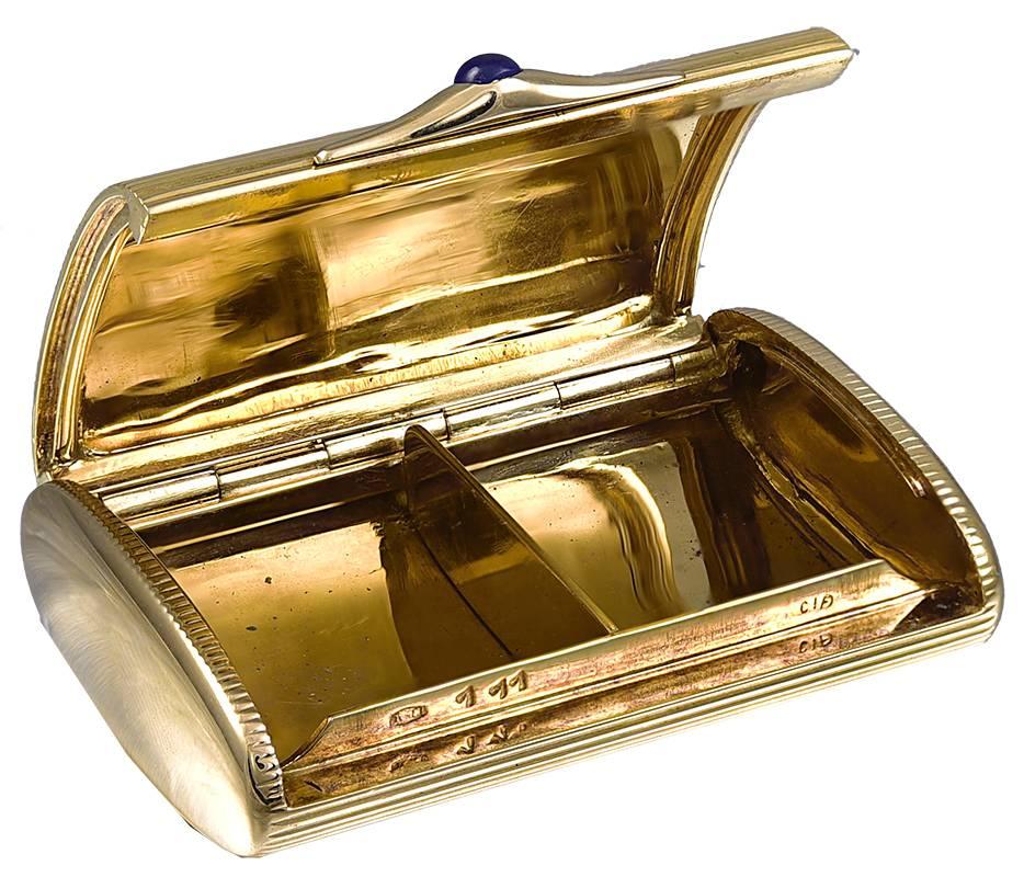 Outstanding pill box with a gold divider to help separate pills.  Extra heavy gauge 18K yellow gold.  Cabochon sapphire closure.  Top and bottom have an engraved line pattern; the sides are shiny gold.  1 1/4" x 1 3/4."  Softly rounded;