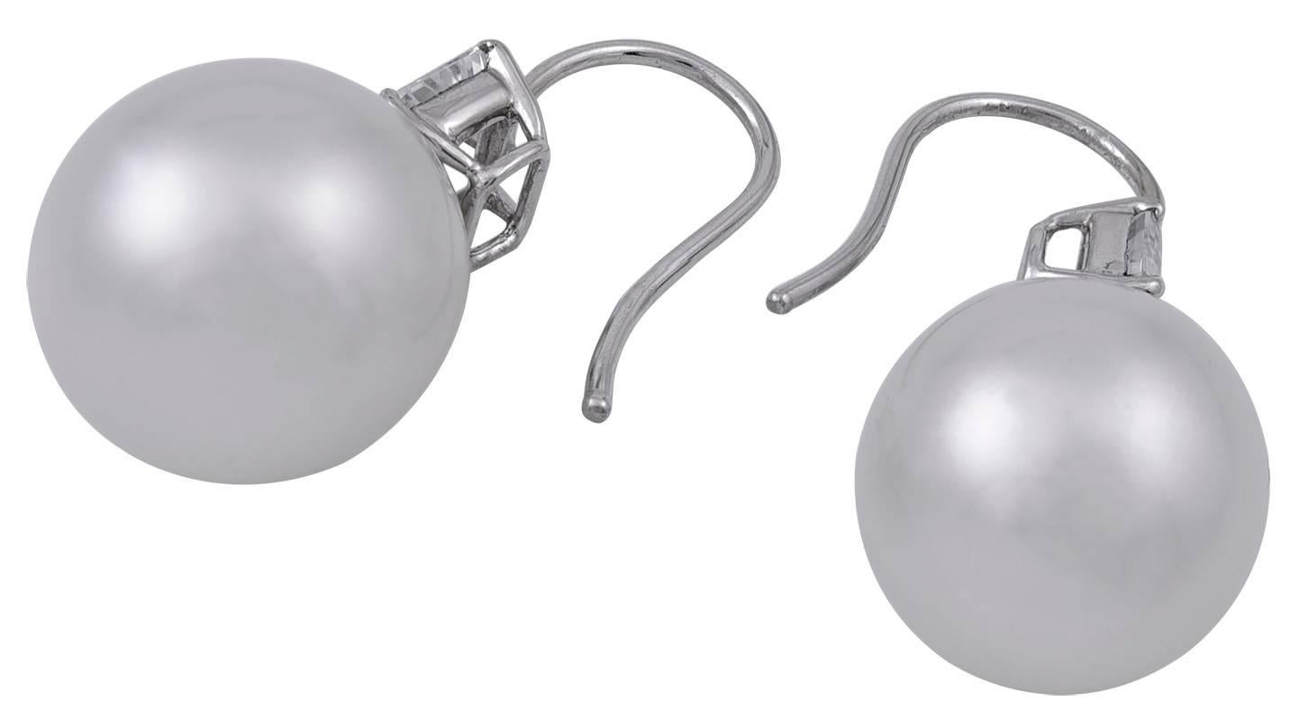 Luscious large South Sea Pearl earrings.  15mm.  Beautiful luster.  Creamy satin color. Set with emerald-cut white sapphires, weighing approximately 1.50 cts.  18K white gold mounting.   These earrings look important and frame the face