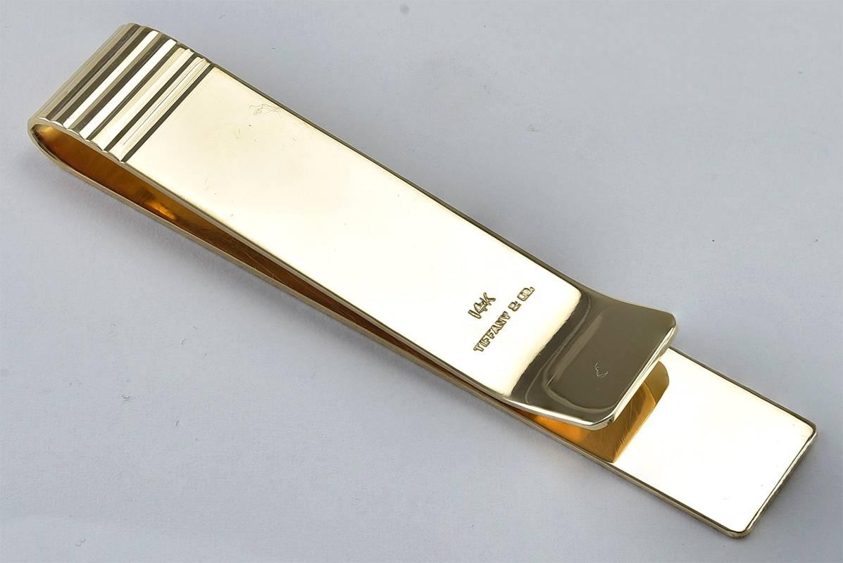 Very crisp and handsome money clip. Made and signed by TIFFANY & CO. 14K yellow gold with a deep deco line pattern. 2-5/8
