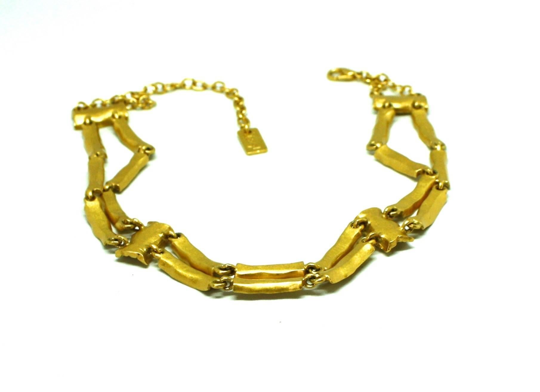 Very stylish brushed gold plated choker by Yves St Laurent from the 1980's. The choker is very unusual because it has been designed to be worn in two ways. One side is a smooth brushed gold plate and the other side has a textured effect. The