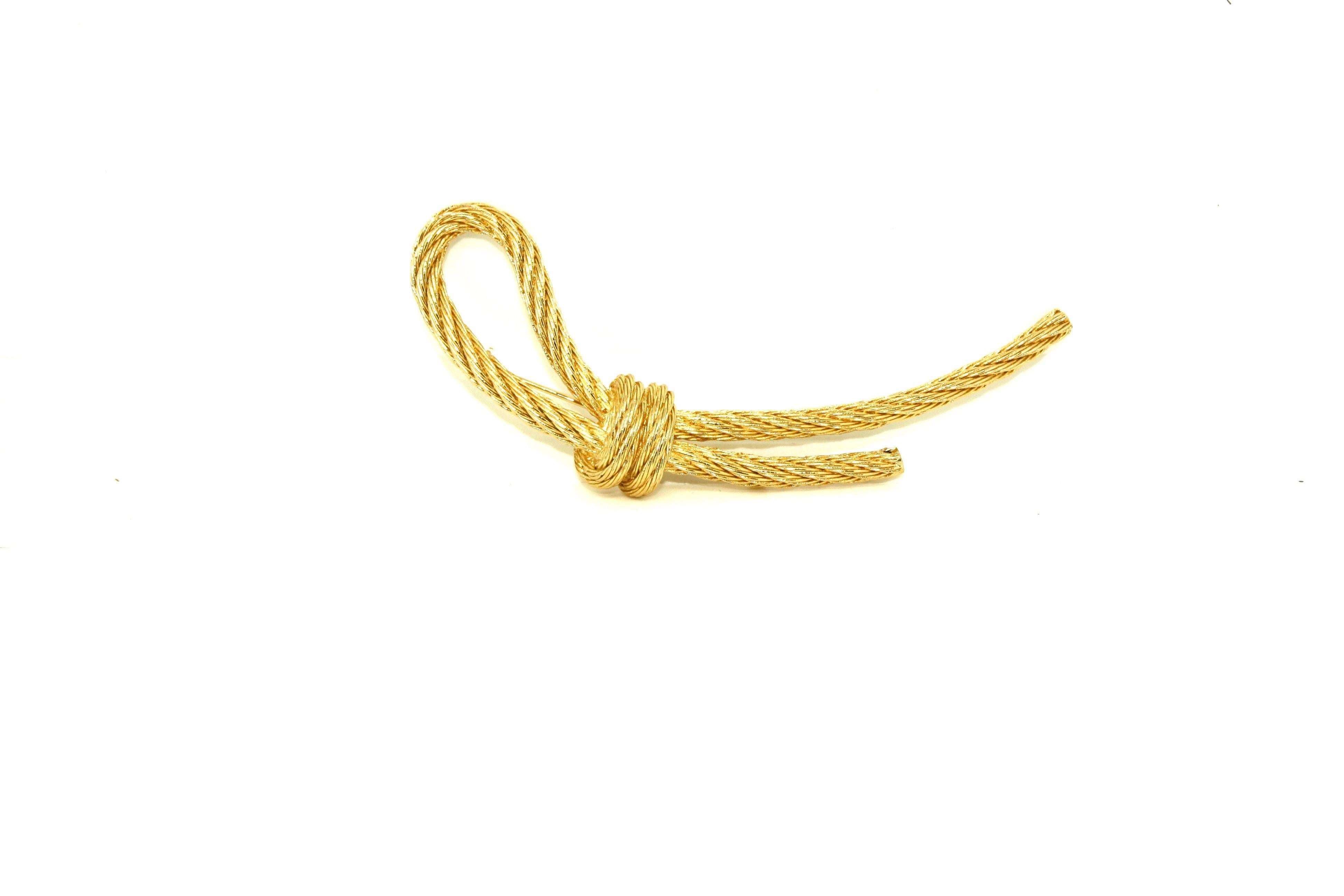 Elegantly styled in a way only Dior can! This gold plated knot brooch by Christian Dior has been dated to the late 1980's. The gold plated base metal has been given a textured finish to look like a rope tied in a knot. The reverse is marked with