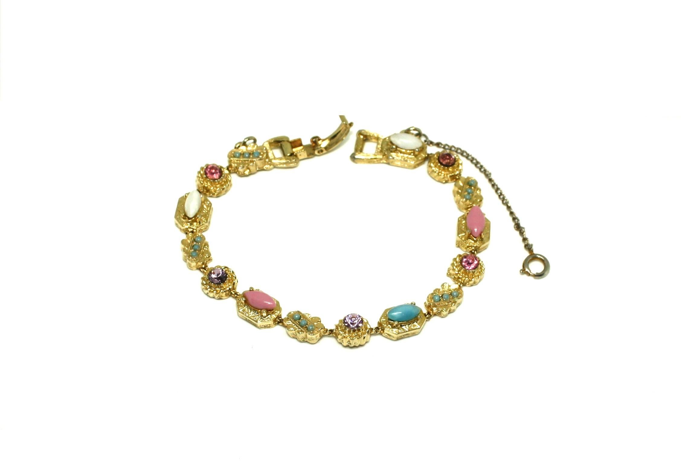 Dated to the 1950's, this delicate link bracelet is extremely detailed. Featuring pretty pastel coloured stones in lilac, pink, white and turquoise set into detailed gilt plated base metal links. The bracelet features a fold-over clasp with the ART
