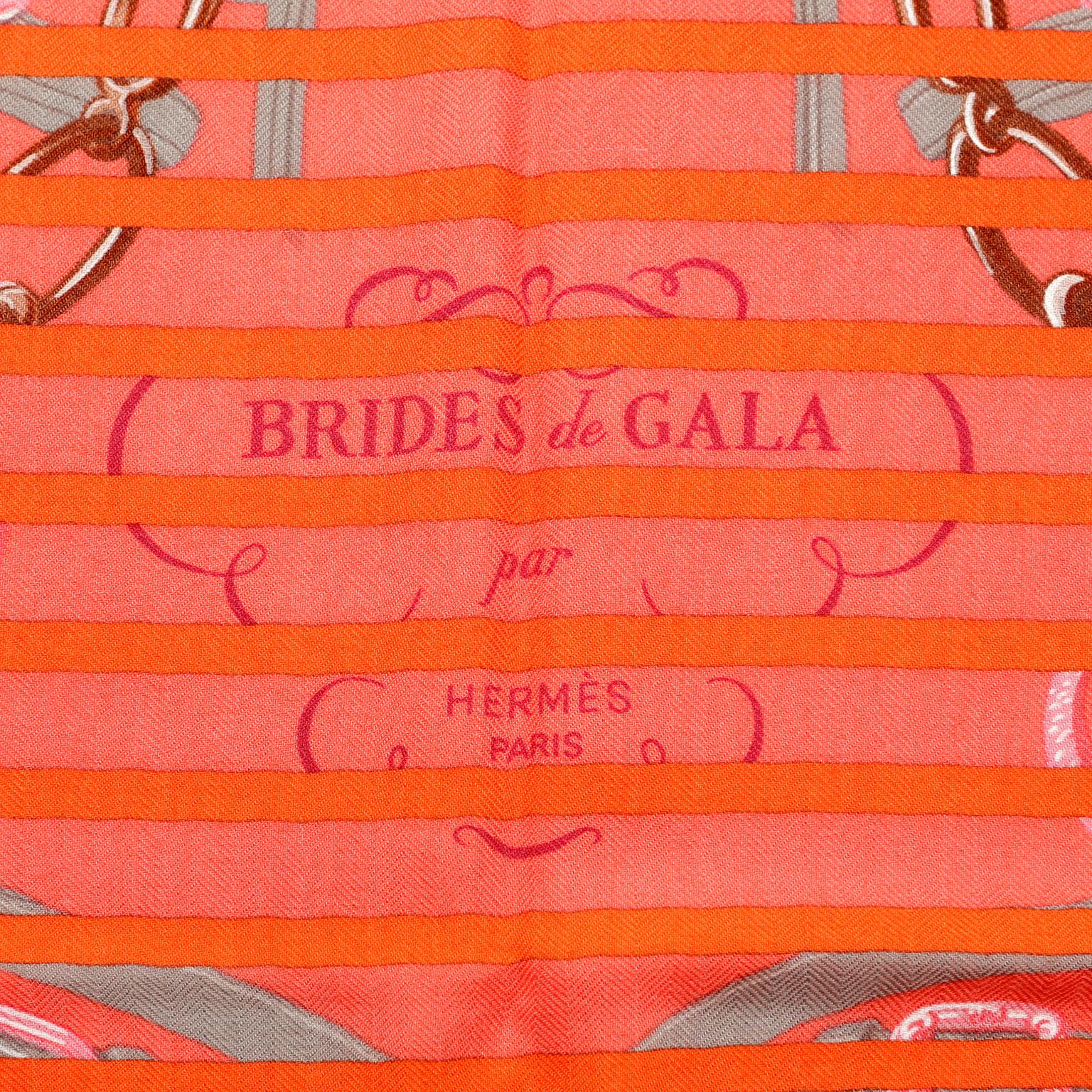 Hermès Red Brides De Gala Cashmere Silk GM Shawl- PRISTINE; never worn.  
Versatile and collectible, the vibrant colors of this classic print are highly desirable. 
Equestrian theme featuring saddles, belts and stirrups. Red with orange striping,