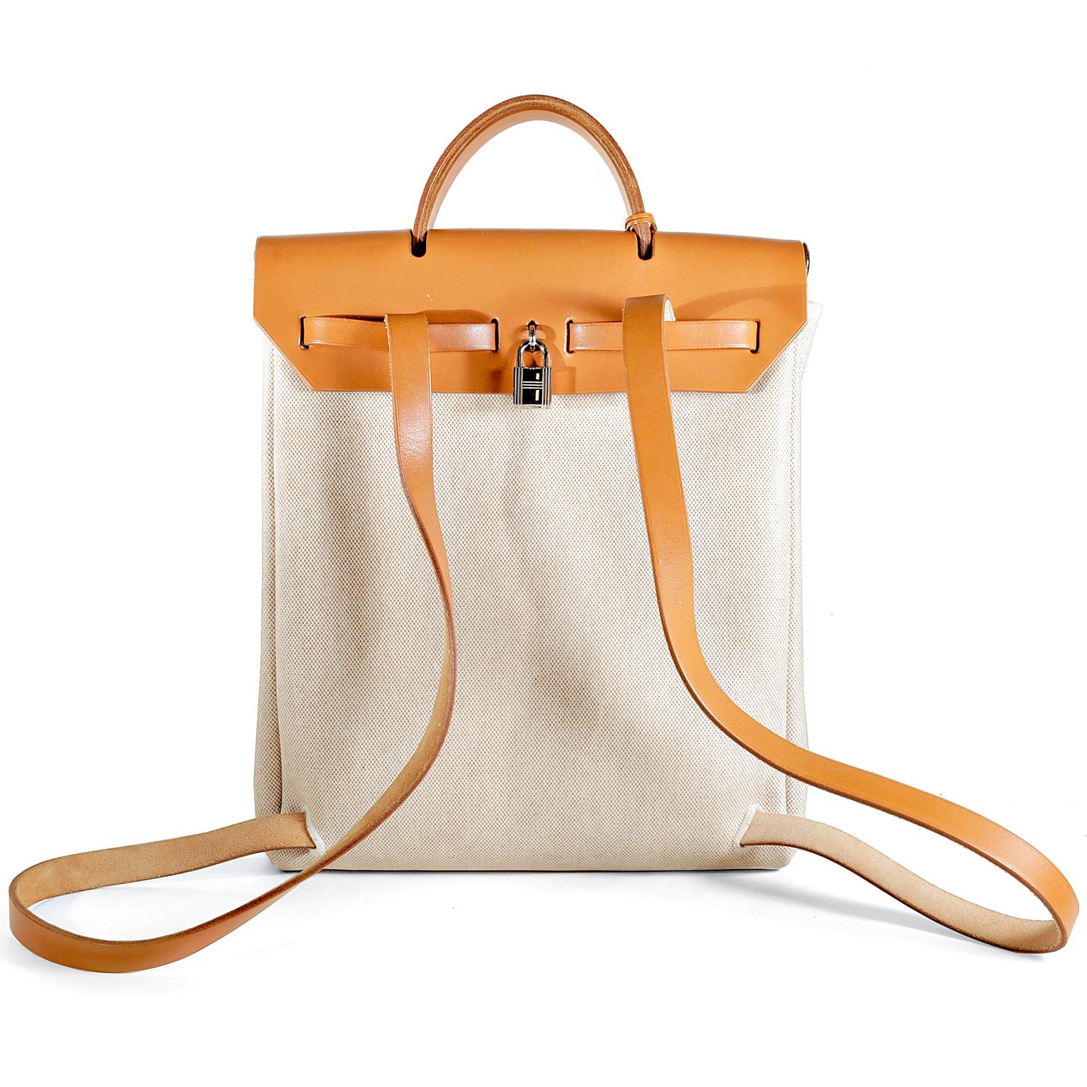 Hermès Toile Her Bag Backpack- Pristine; appears never carried.     
The Her Bag is comprised of Sand toile fabric with a sturdy natural brown leather top.  It has a similar belted closure like the Kelly but with a far less demanding price tag. 