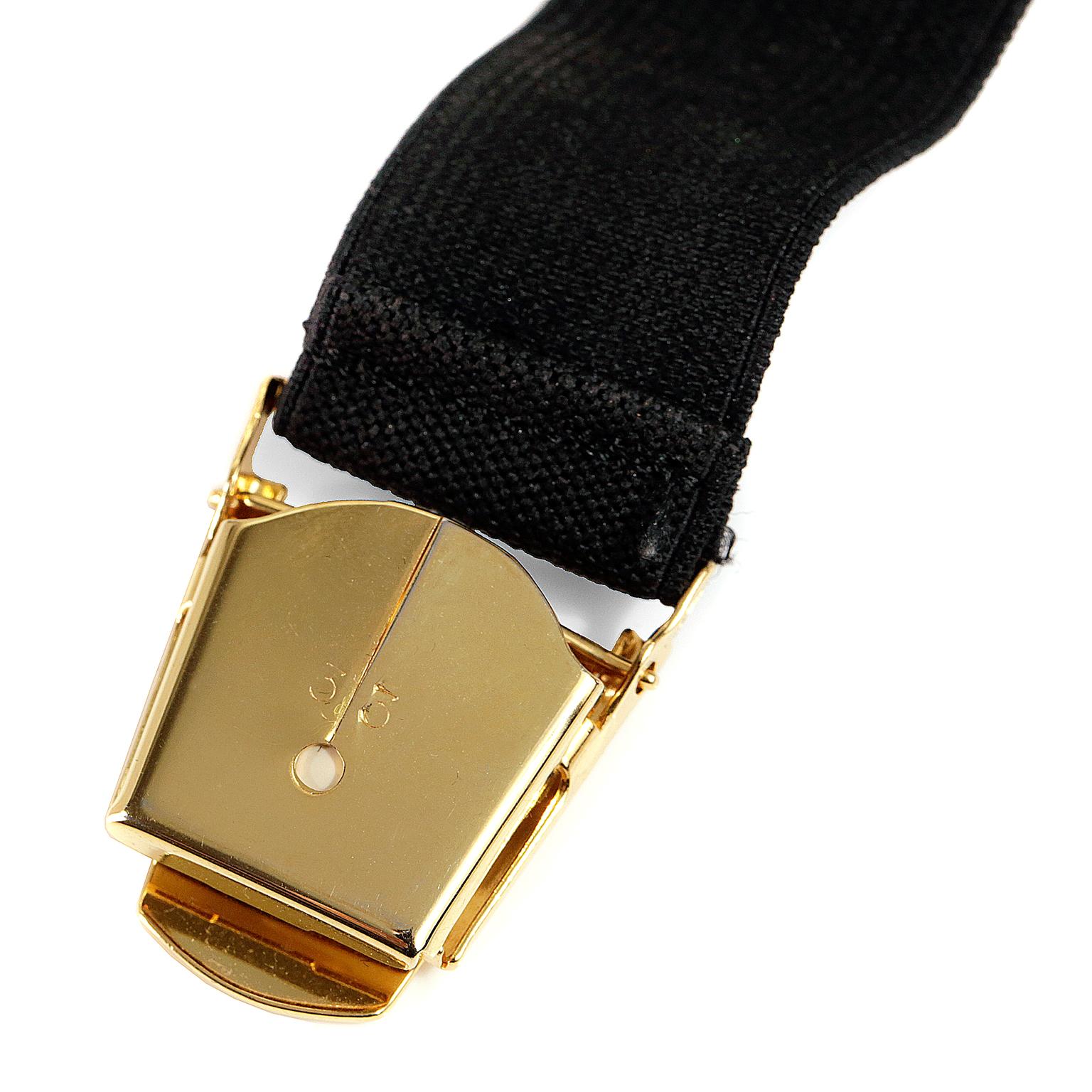 This authentic Chanel Black Elastic Clip On Cincher is in excellent condition.  Perfect for tightening up the back of a blazer, jacket or sweater.  
Black elastic with CHANEL in white letters.  Gold clips on either end. 
Proudly offered from Only