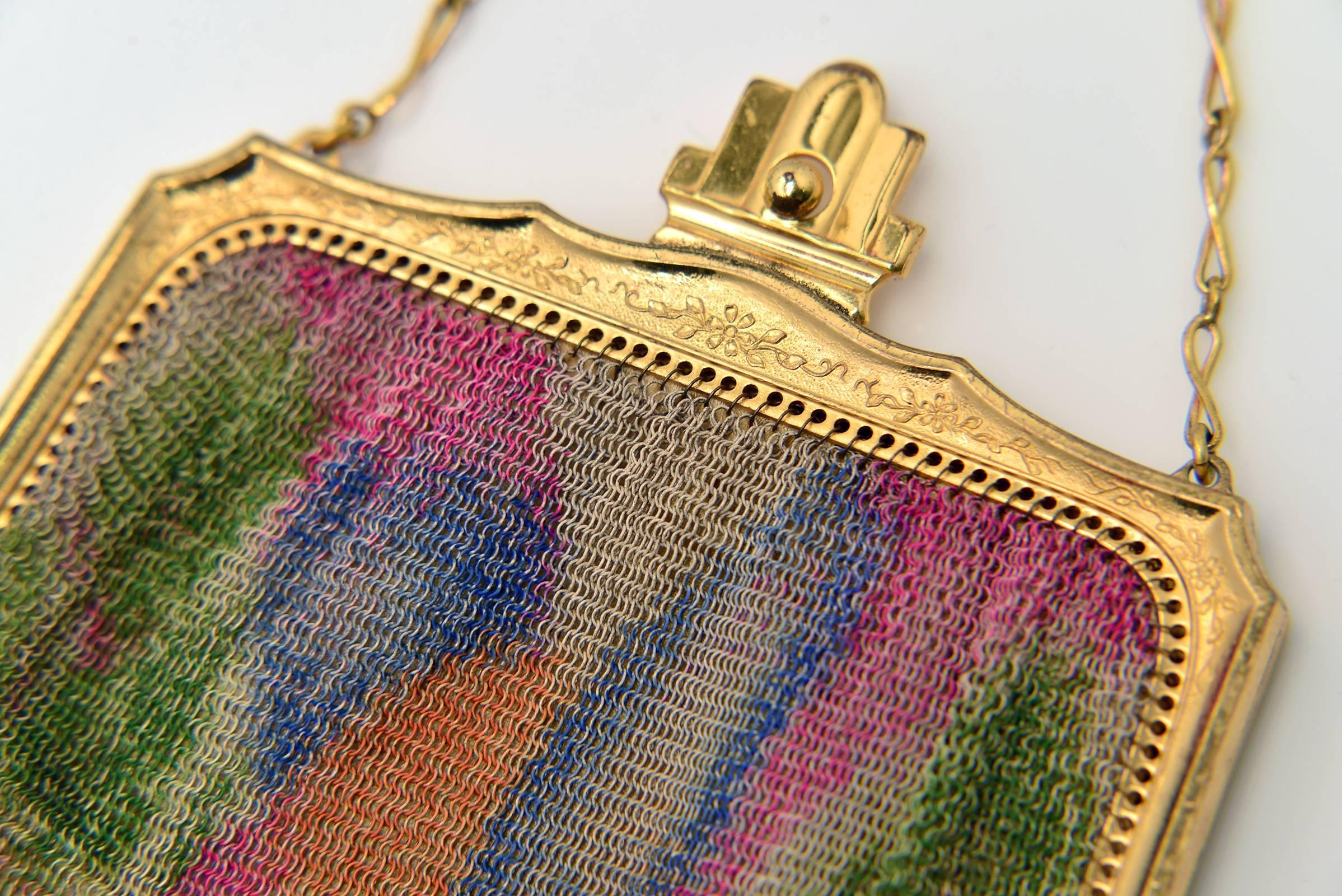 Highly collectible Whiting and Davis mesh purse. This hand bag features painted mesh with an Art Deco frame and a yellow silk satin lining. The Art Deco abstract motif is hot pink, blue, orange and green and on both front and back. The bag features