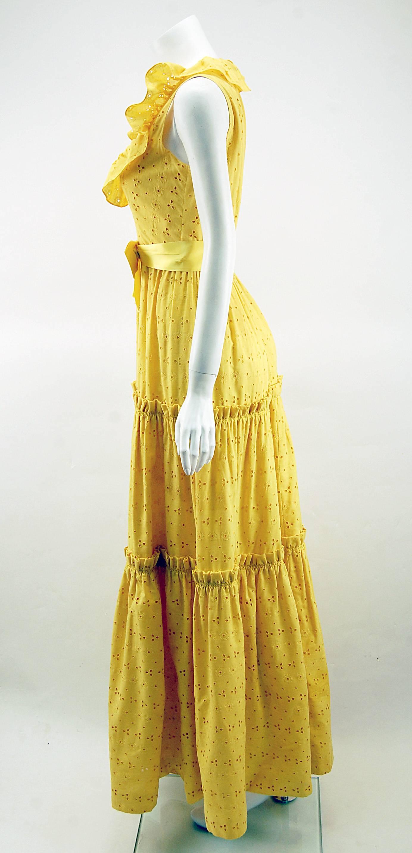Adorable yellow summer dress by Mollie Parnis. The neckline is cut deep with a ruffle all the way around. Fitted bodice gives way to a three tiered gathered skirt that hits the floor. Sweet silk satin attached, yellow waist band and bow. The fabric