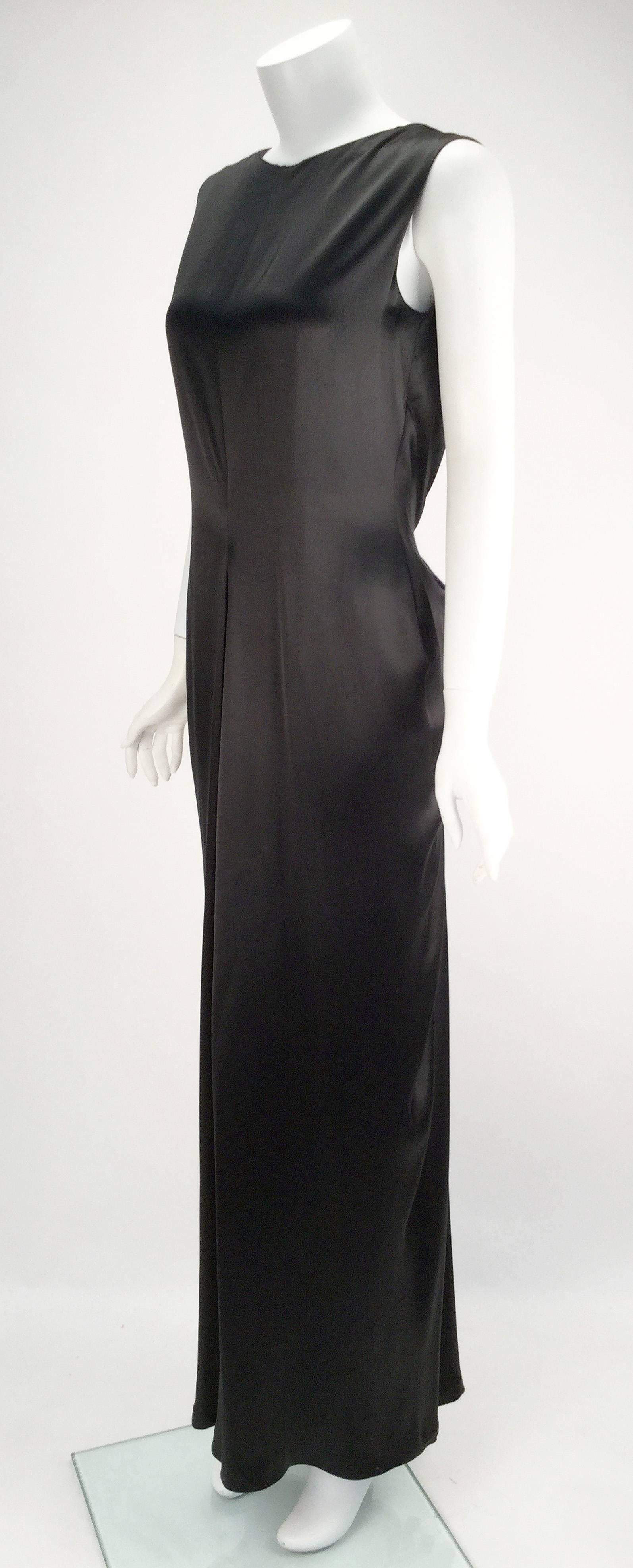 Timeless and classic, this black satin Oscar dress exudes grace. The front is a modest cut with a center pinched waist. The back is gathered at the back of shoulder, while the dress dips in to a deep V. Pleating and gathering at the low back near