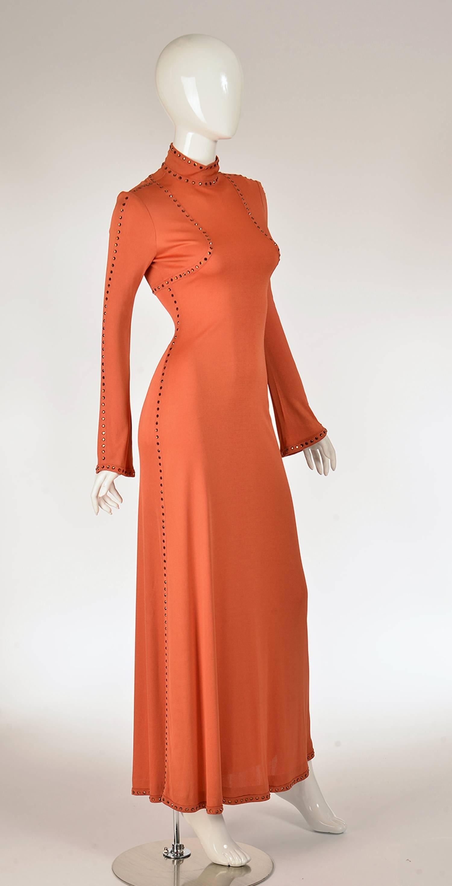 Late 60's striking burnt orange evening dress by Ayako for Imagnin. This high-neck, long sleeve, floor-length evening dress has designer princess seams on the bodice that are covered with Orange rhinestones. The rhinestones continue as design lines