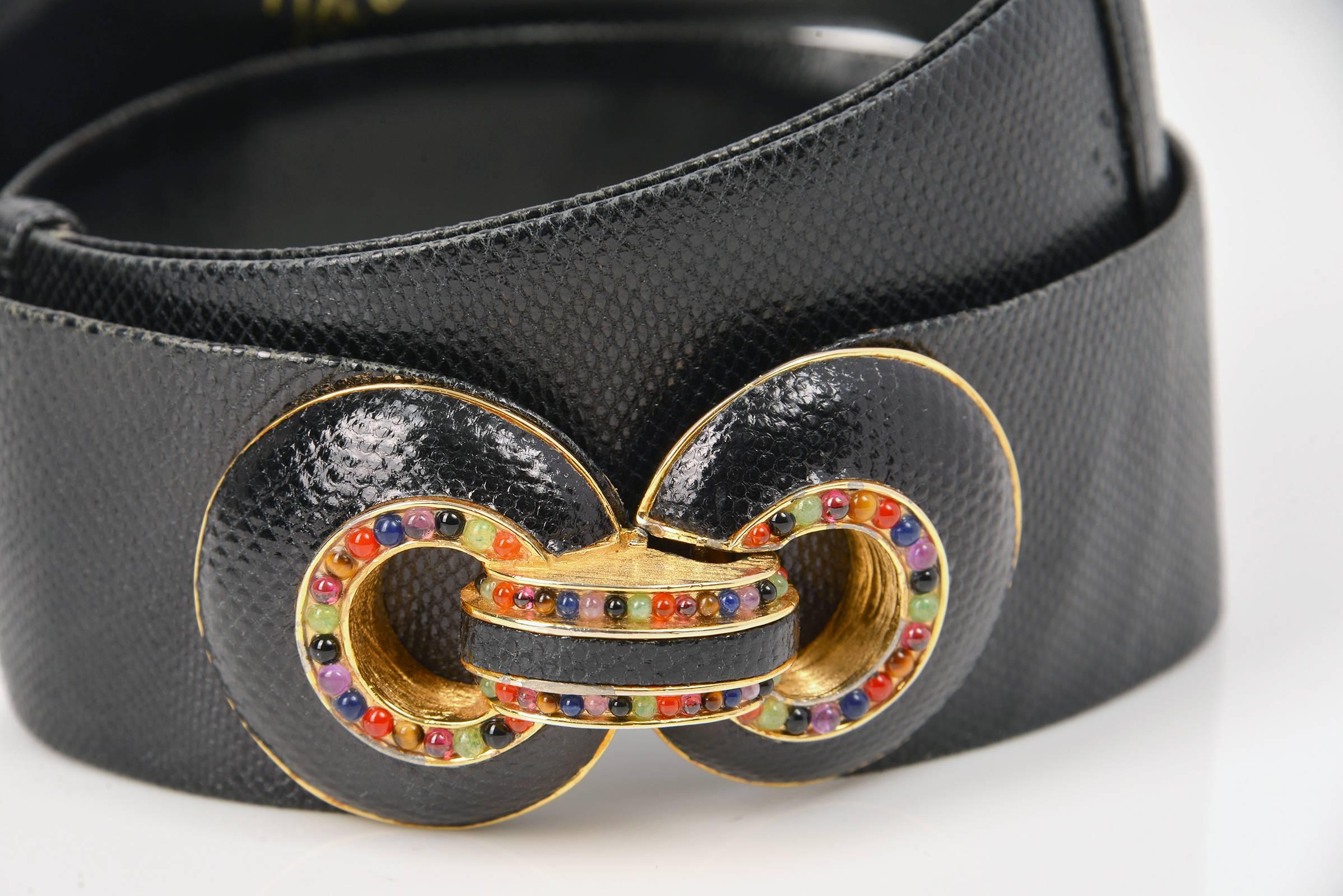 Vintage Judith Leiber belt. This belt is primarily composed of embossed black leather, and features a gold buckle. The two-piece gold buckle is in the shape of two loops, side by side. Both loops are embossed black leather, and have a ring of small