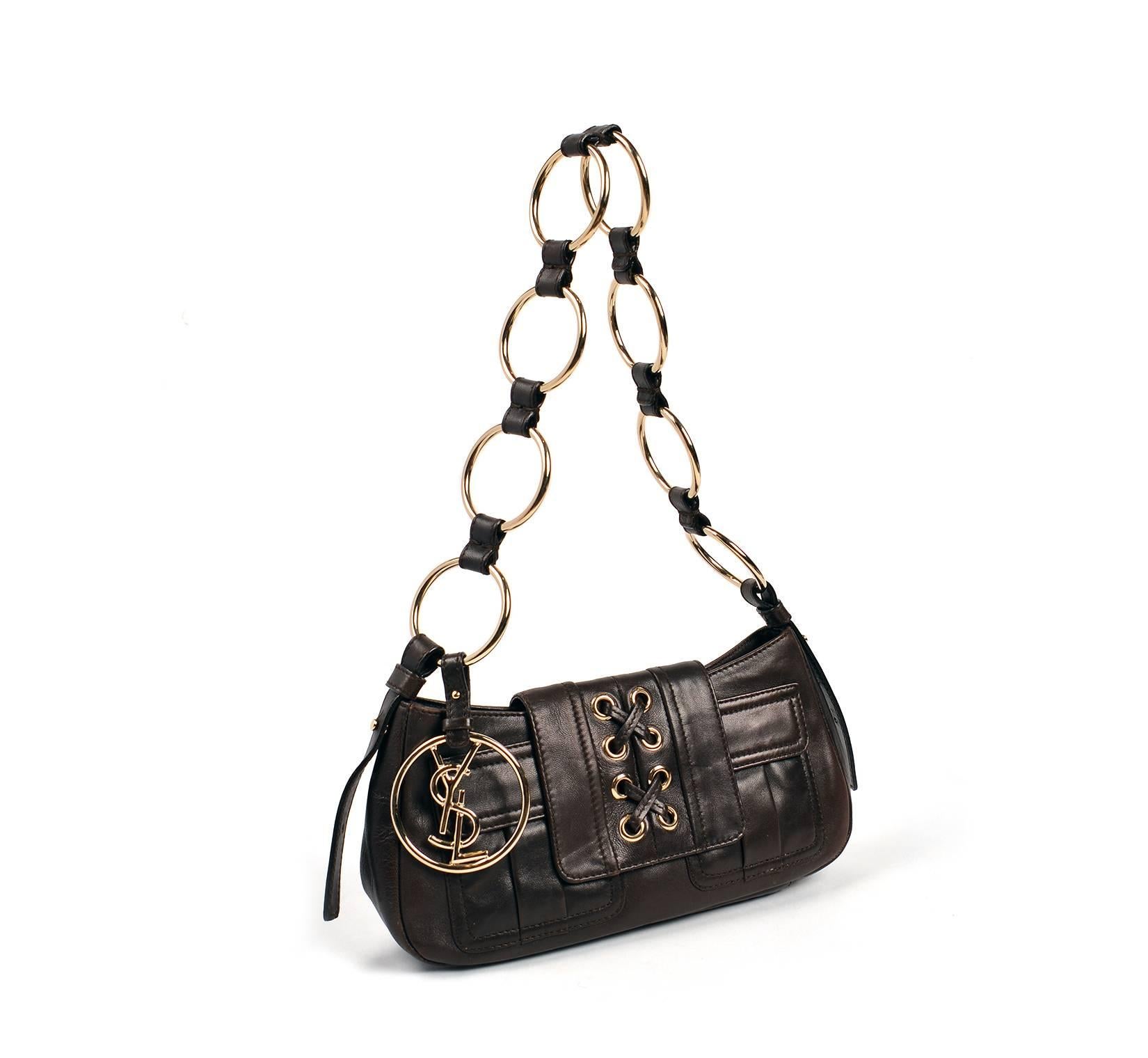  The purse is composed of soft and supple chocolate brown leather accented by silver hardware. The body of the purse features a lace-up pattern on the flap, as well as two box pleat flap pockets. The strap of the purse is composed of silver chain