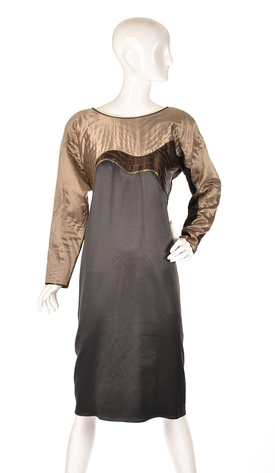 
This late 20th century shift dress by Bergdorf Goodman is absolutely luminous. The dress features a gold-stitched quilted abstract wave design in pale gold and chocolate fabric over a deep black satin. The neck, sleeves, and bottom of bust are