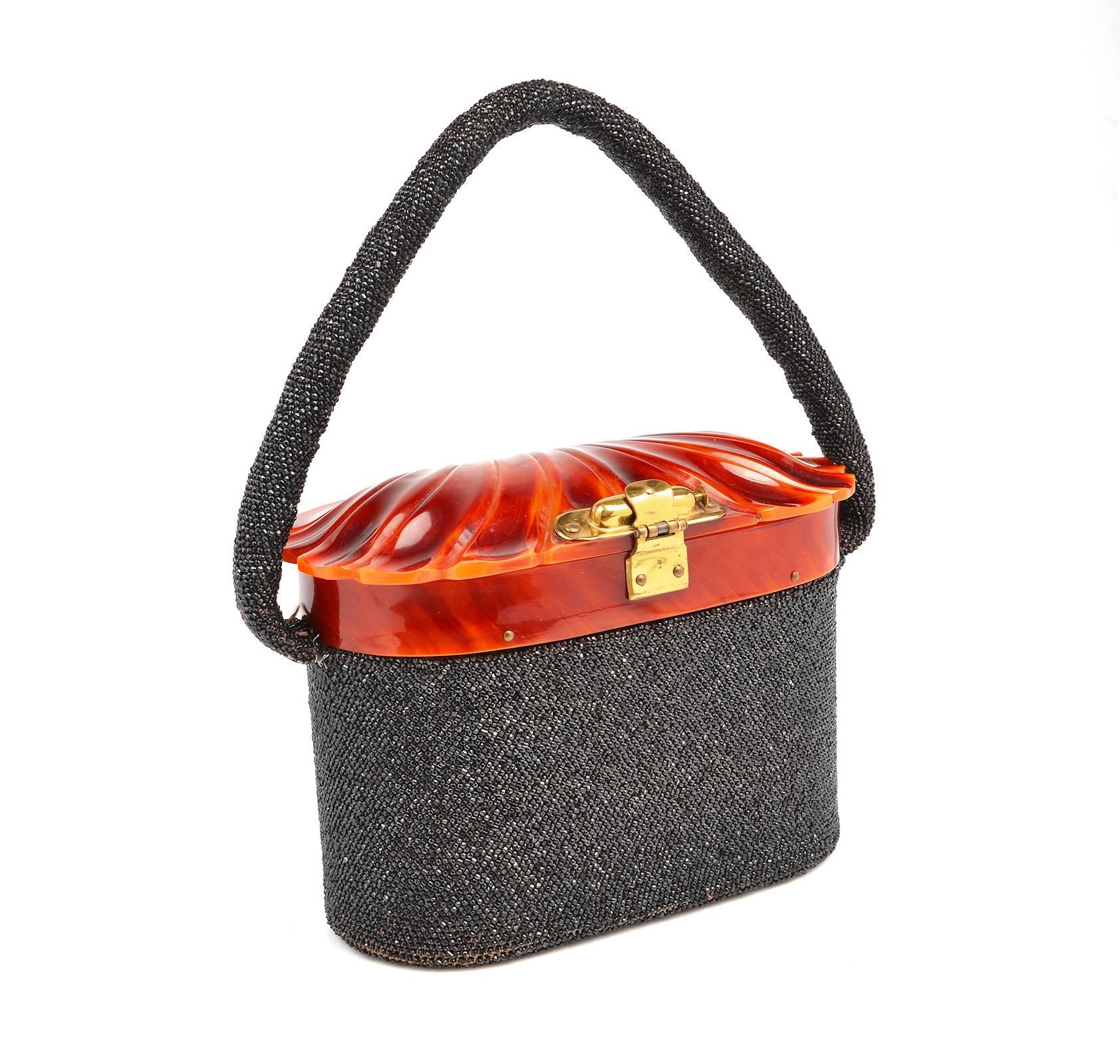 Refined 1940s carnival glass beaded thermoset handbag. Extremely rare that a seed box bag of this early origin is in such amazing condition.  The oblong-shaped purse features a tortoiseshell-tone thermoset lid, molded into an elegant scallop Venus