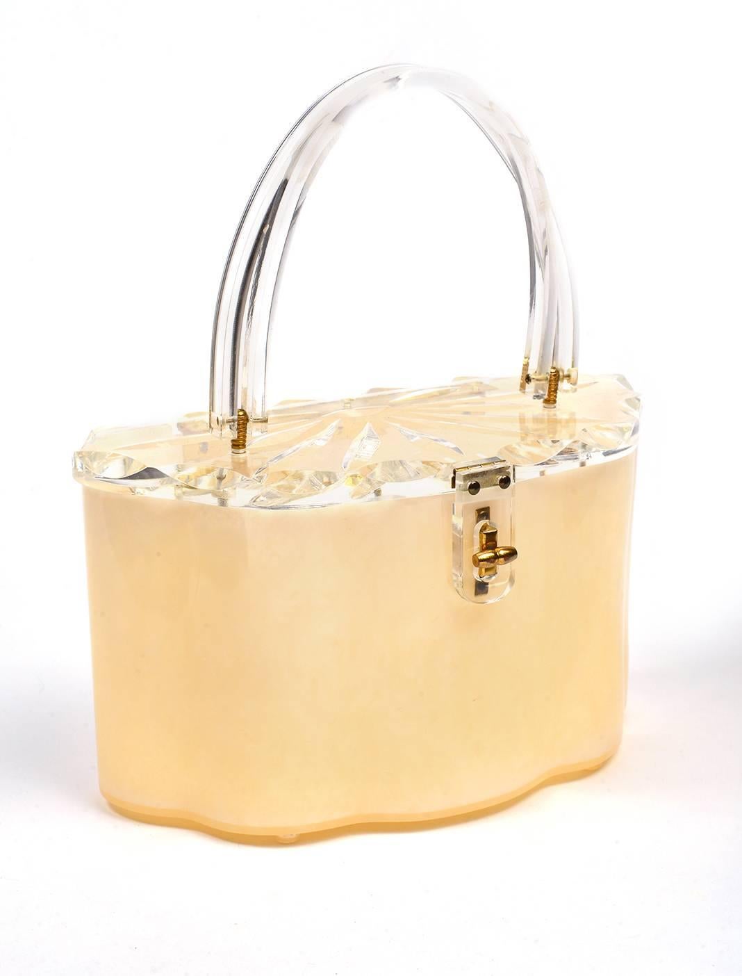 
Ravishing scalloped Lucite purse is something all on its own. Clear lid with carving's of half of a flower with the center and nine petals. The edge is also carved with a leaf like pattern which continues around the lid. The handle is clear and