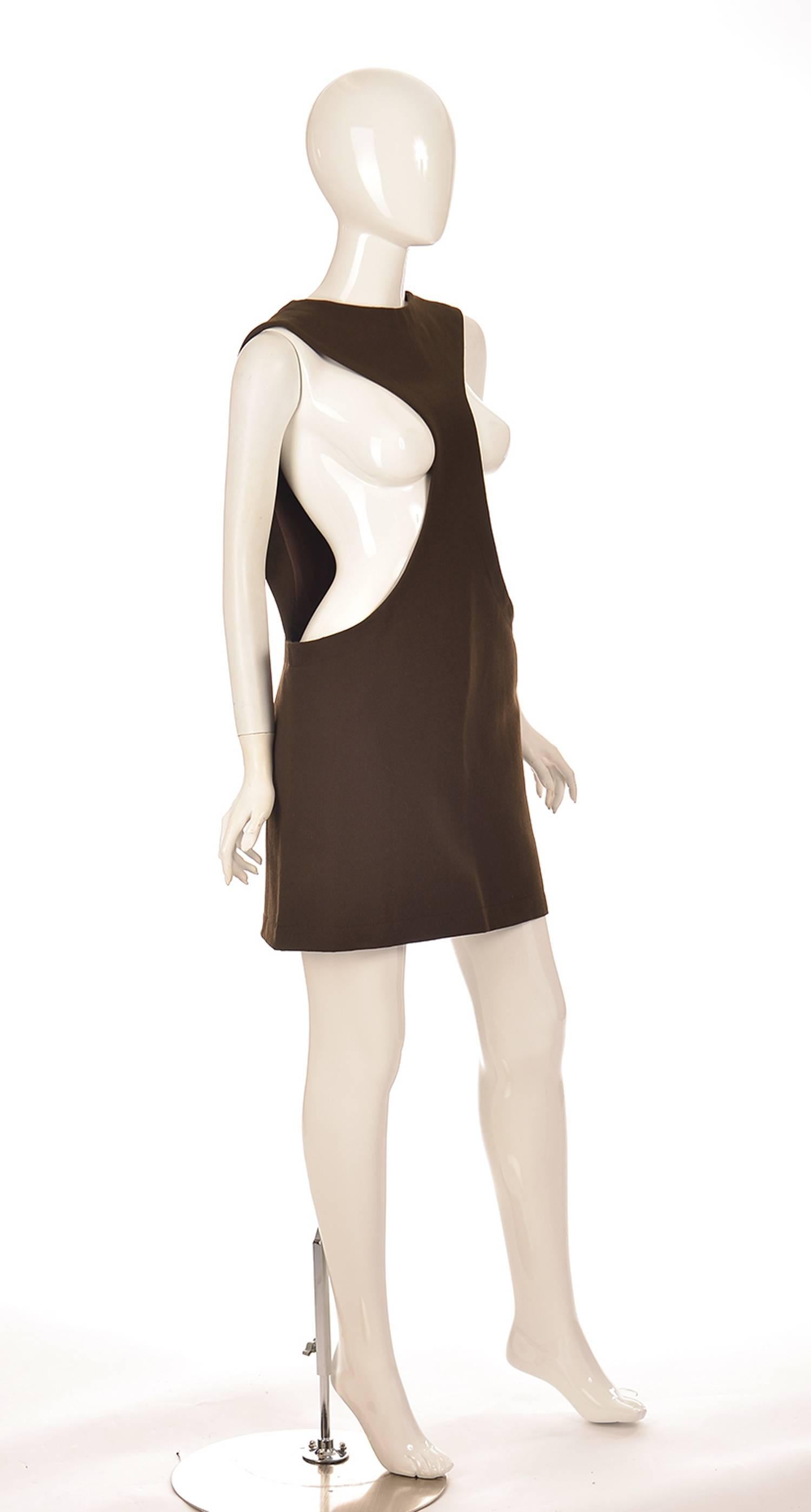 
This chocolate brown jumper by Pierre Cardin features a distinctive narrow front and open sides. Stitching curves gently along the edges of the garment's hem, skirt, neck, and tapering front. The striking jumper is fully lined and has two hook