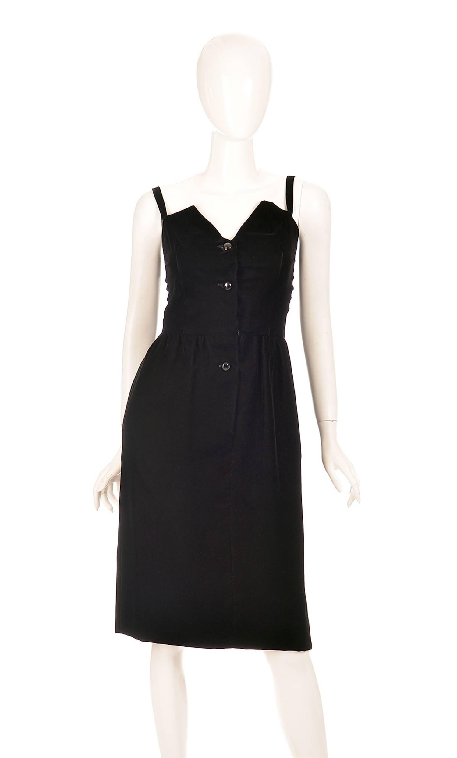 A 1970's Givenchy chic, black, velvet dress made of Viscos and Cupro. The dress features an angular geometric sweetheart neckline with spaghetti straps, buttoned up with polished geometric radial cut black buttons. This dress is knee length, and was