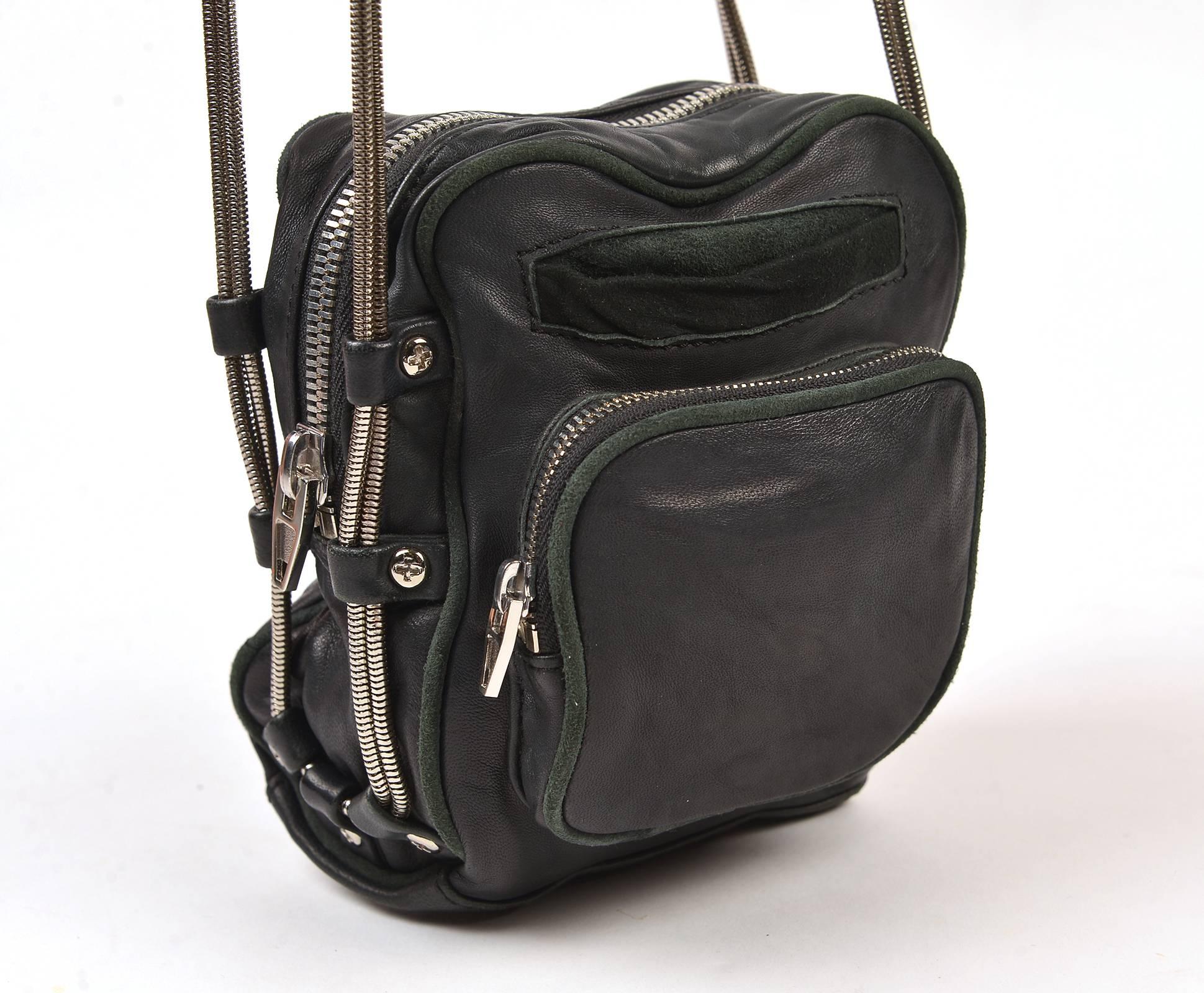 The bag is composed of soft, relaxed, black leather and striking silver-tone hardware; a perfect combination of luxurious materials and edgy design. The body of the bag is rectangular in shape and features a prominent zippered pocket in front, as