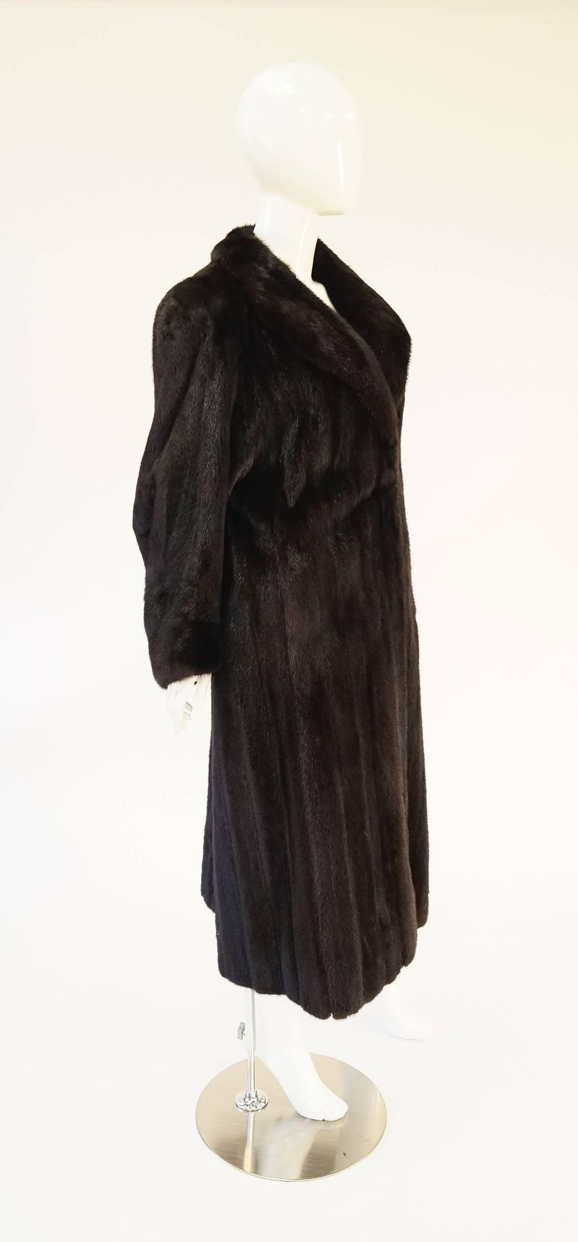 
This plush brown mink coat is absolutely stunning. The coat features a shawl collar that can be turned up to protect the wearer against the cold. Long, voluminous sleeves. Ankle length. The sumptuous dark mink and long length give the coat its