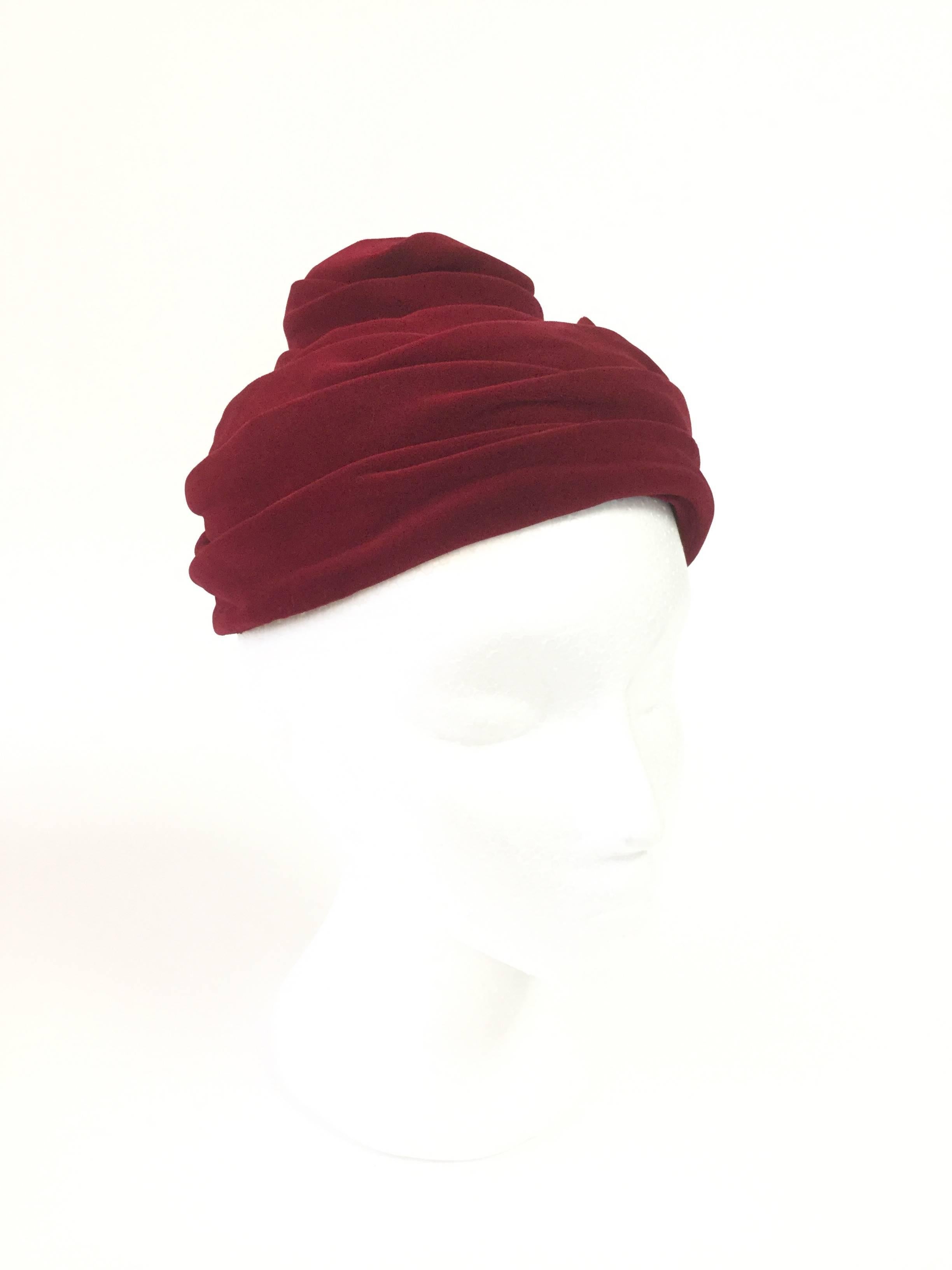 
This absolutely gorgeous toque cap by Miss Sally Victor New York is composed of multiple undulating folds of red velvet. The toque cap sits delicately on top of the wearers head and features a notch in the back as both a design element and as a