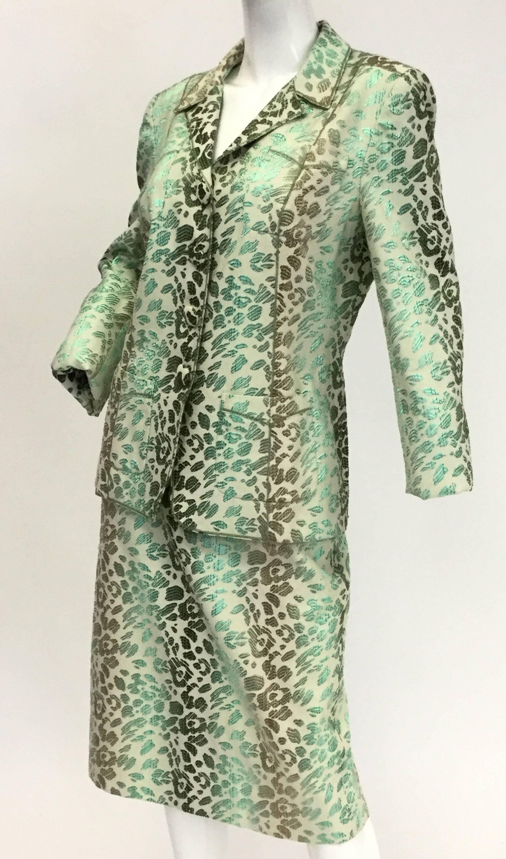 
Stand out from the crowd in this gorgeous suit by Oscar de la Renta! The ecru based fabric pops with color and movement thanks to the striking green ombre brocade cheetah print. The four-button blazer has a notched collar and two pockets at both