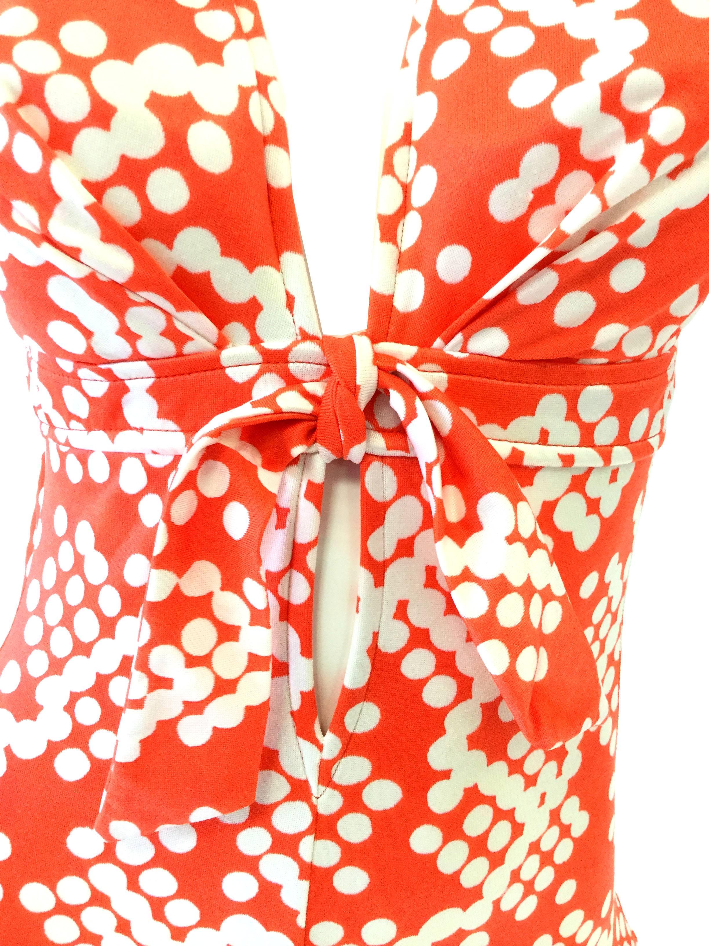 
This adorable polkadot cluster print in white and red swimsuit features a plunging neckline accented with an under-the-bust sarong tie. The suit has a boy-short bottom, a plunging back, and intriguing adjustable halter-like straps that connect at