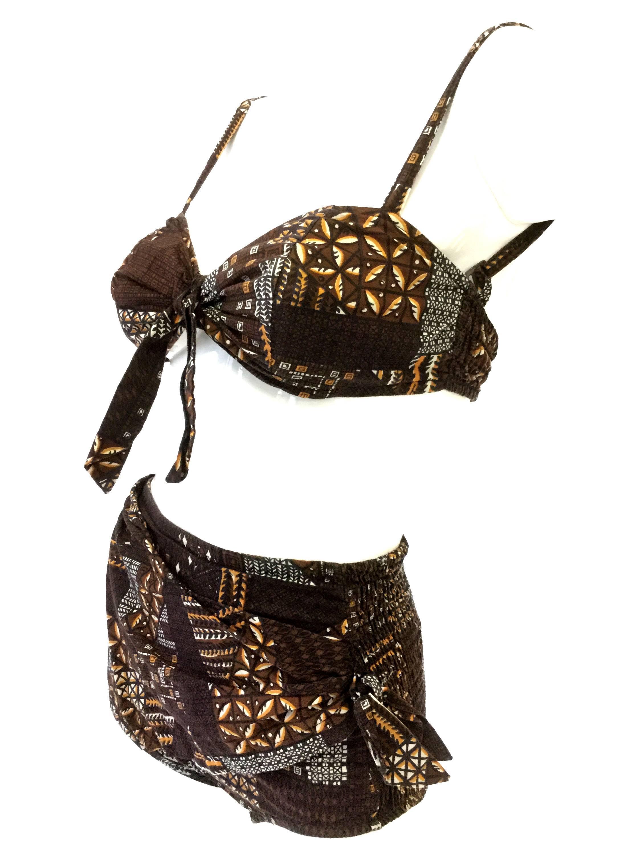 
This print bikini is an absolute dream! The high waisted boy-short bottoms have a sarong-style draped side tie, and the sweetheart bra top gathers in the middle with a relaxed bow. The bikini features a geometric batik-style print in chestnut
