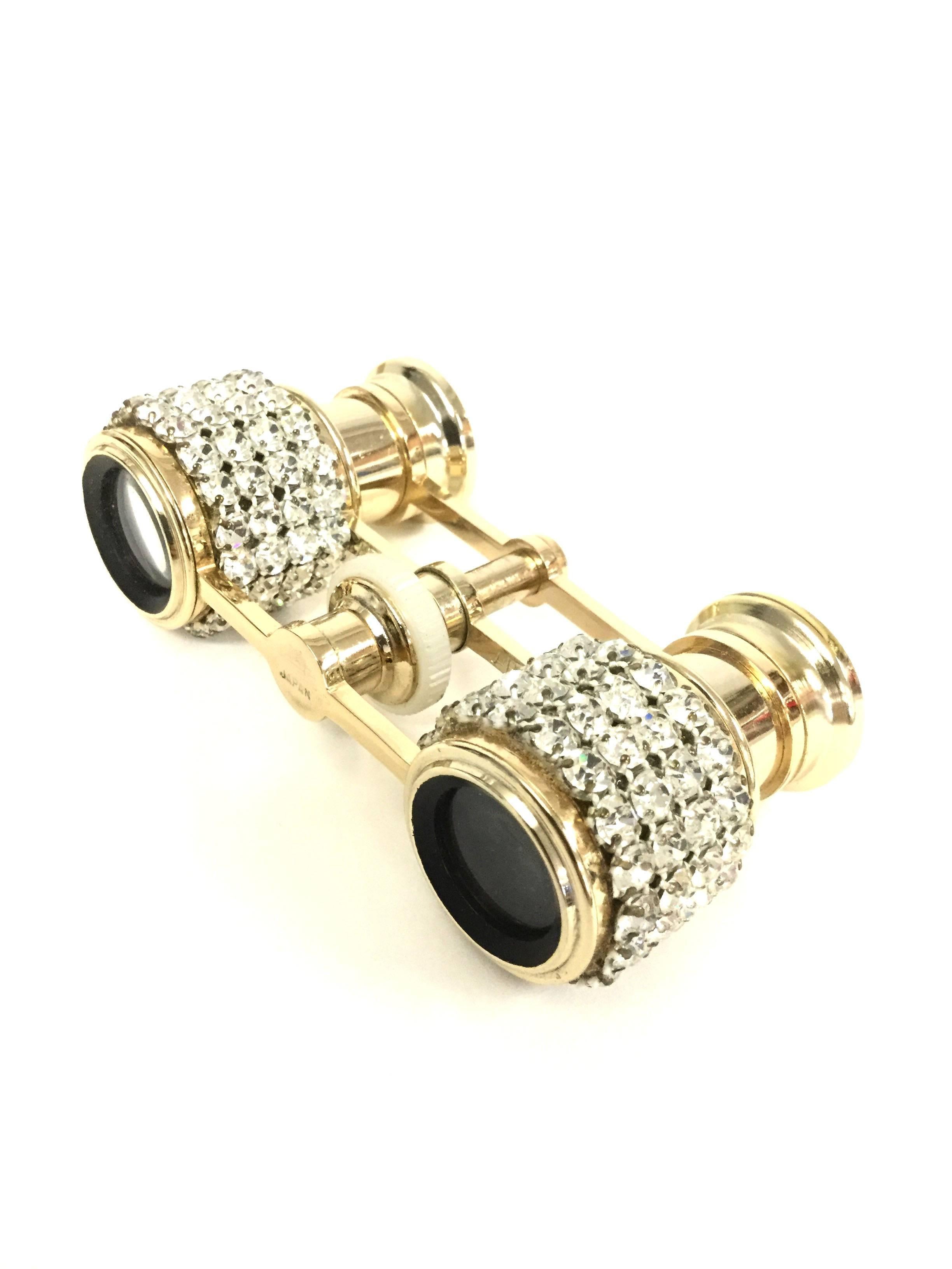
These midcentury opera glasses by Mignon Japan are undeniably glamorous. The gold tone glasses feature four rows of rhinestones on each sight barrel with a thin, elegant bridge suspended between them. Included is the original soft, padded,