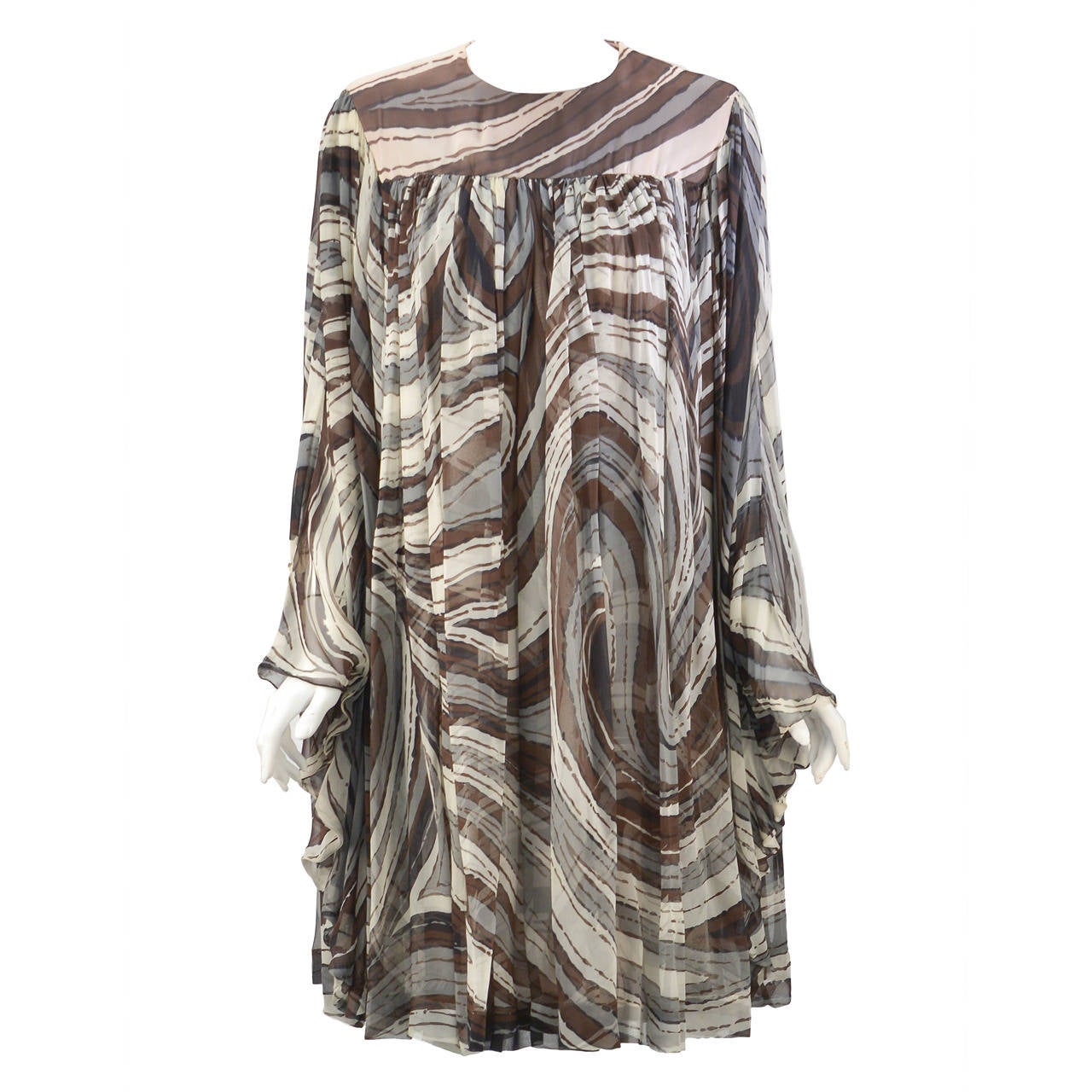 This 1960's Donald Brooks multi brown silk dress with its dramatic batwing sleeves will be all the rave at any event/outing. It looks perfect on every body type. The dress is loose-fitting with gathers in front and back that billow perfectly at the