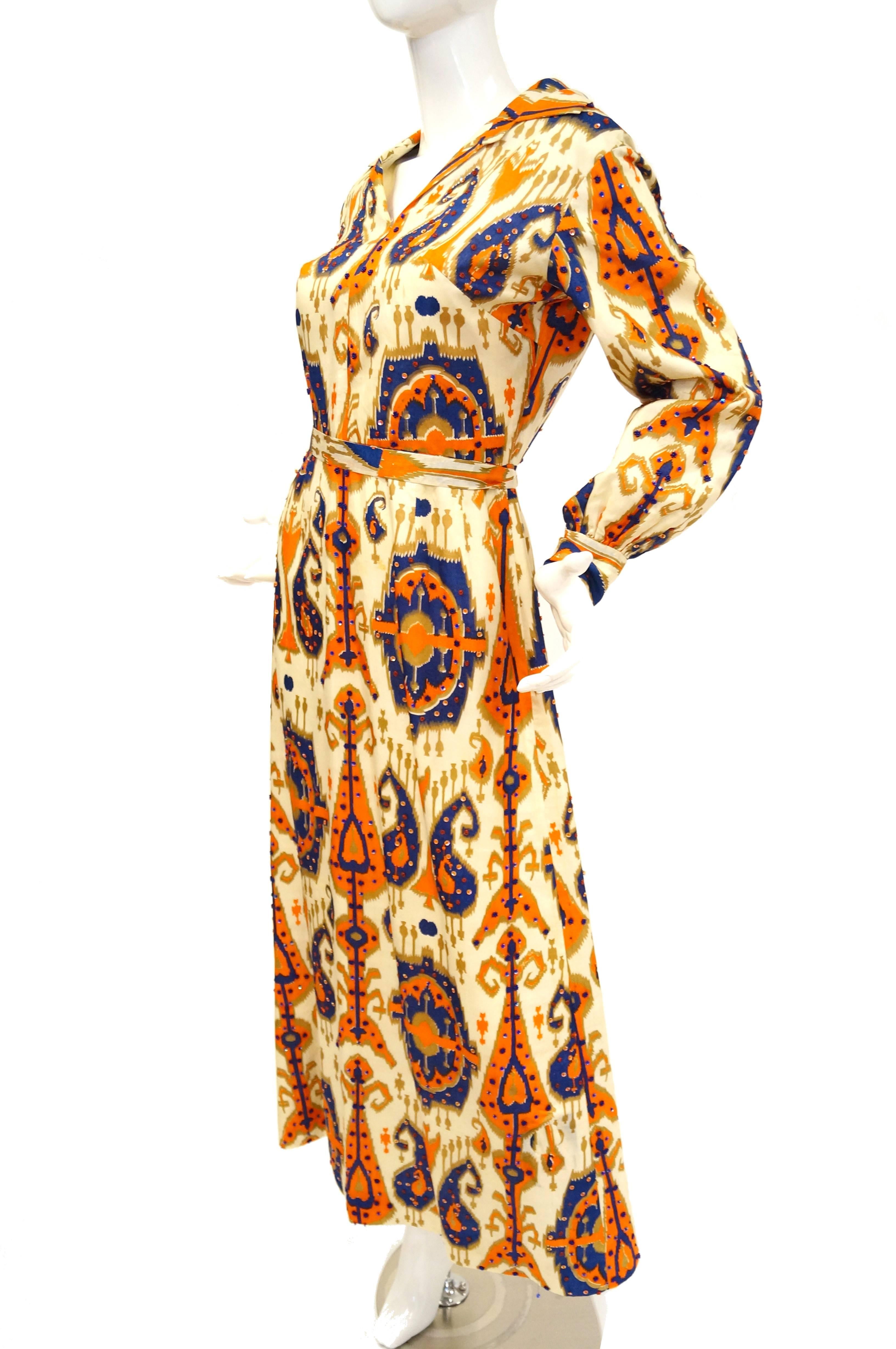 You've found it: the perfect breezy dress for a summer soiree. This 1970s calf - length dress features an A - line skirt, an exaggerated wing collar, voluminous cuffed sleeves, and a cinched waist with ribbon belt. The tan, cream, orange, and blue,