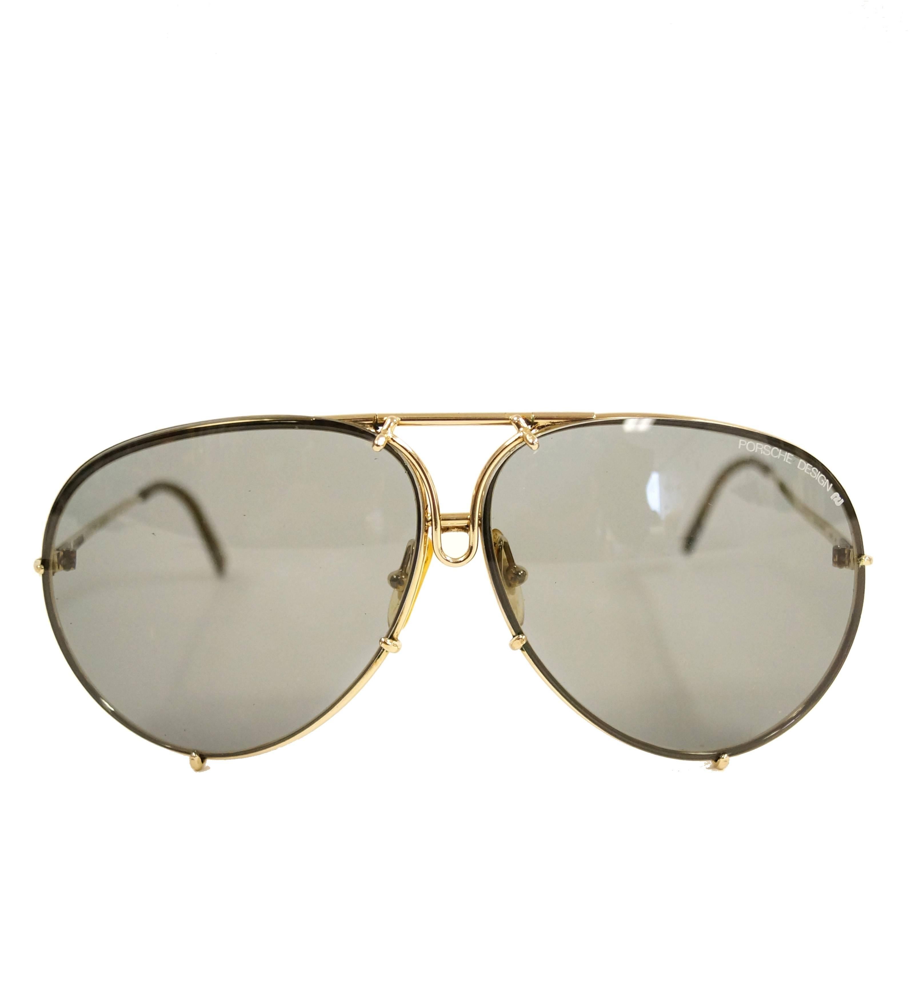 Luxurious gold-tone 1980s sunglasses by Carrera Porsche Design with smoky quartz tint lenses. These model 5621 glasses are composed of a thin gold-tone metal frame that curves smoothly around the lenses. The temples are gold-tone with an amber-tone