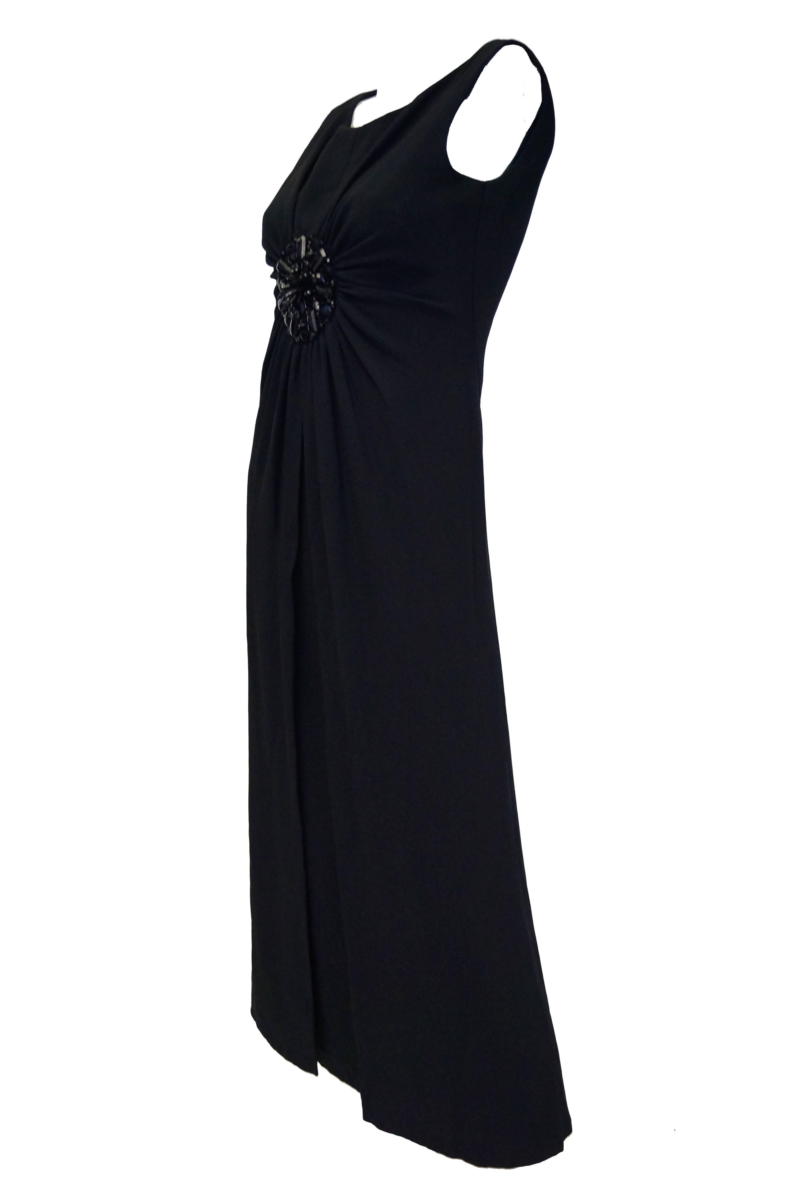 Simply Sublime and Beautiful empire waist gown by Guy Laroche! The black maxi dress is sleeveless with a high scoop neck. The dress features a beautiful cluster of black rhinestones and Rock beads centered on the front of the dress between the bust