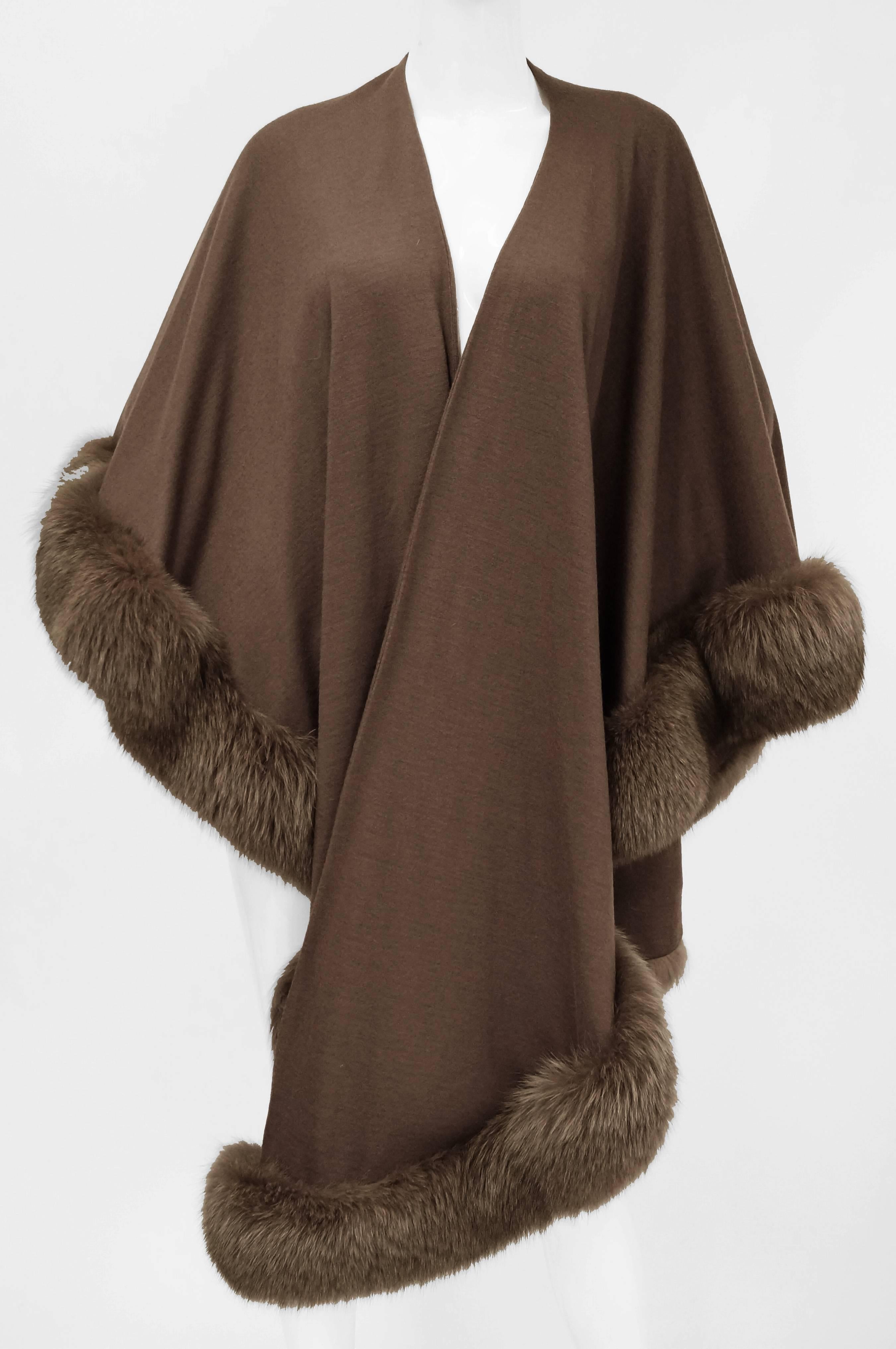 Sumptuous is an understatement! This solid toffee-colored shawl by Adrienne Landau is circularly cut with a straight center line up to the neck. The shawl is made of a medium-weight wool that is weighed down with fox fur trim. The shawl bounces