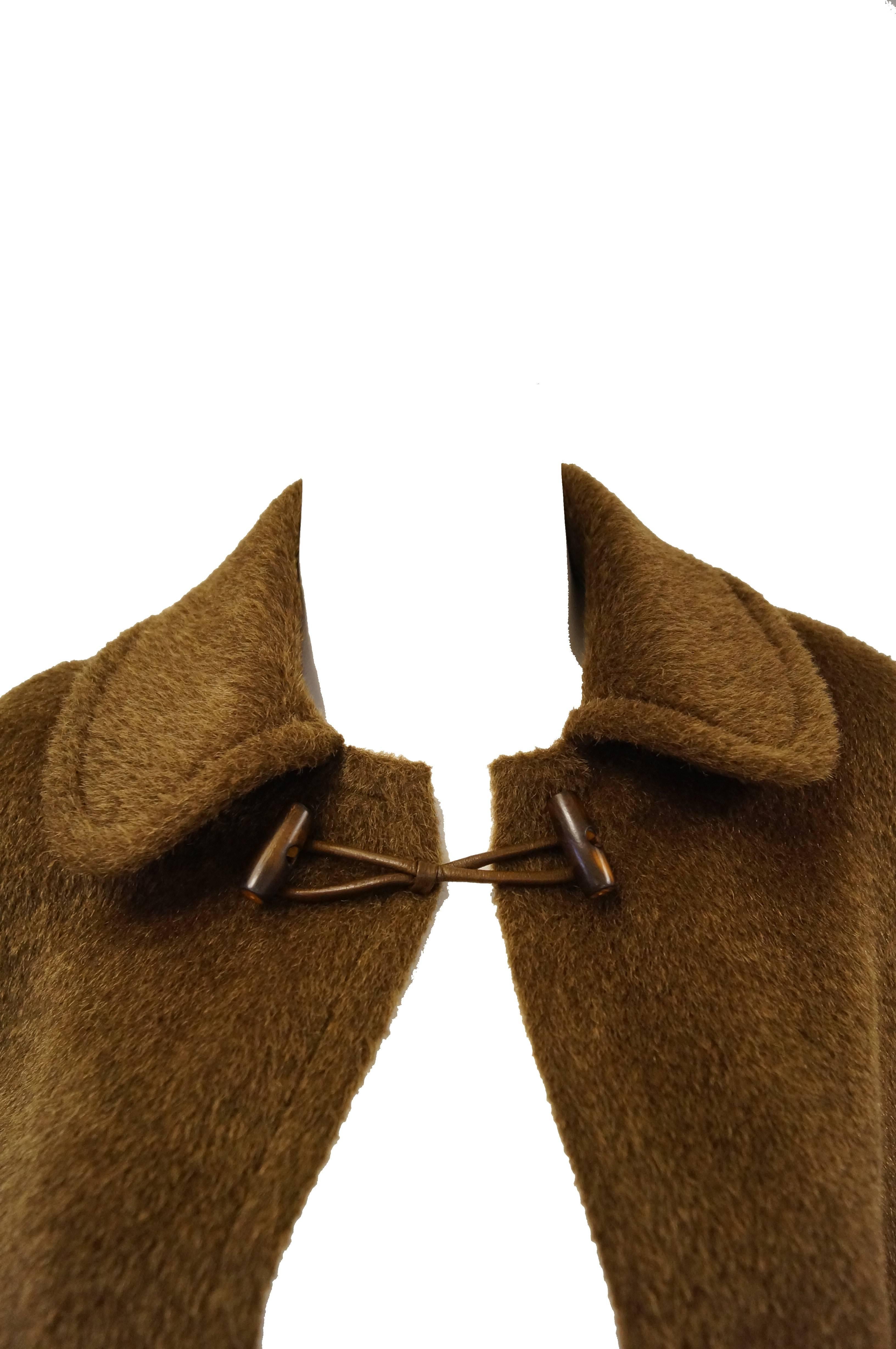 Gorgeous heavy wool cloak by Yves Saint Laurent. The coat features a classic polished wood and leather toggle button at the sturdy square collar (that can be turned up to shield you from the cold!), and is a glamorous shin-length. The cloak is a