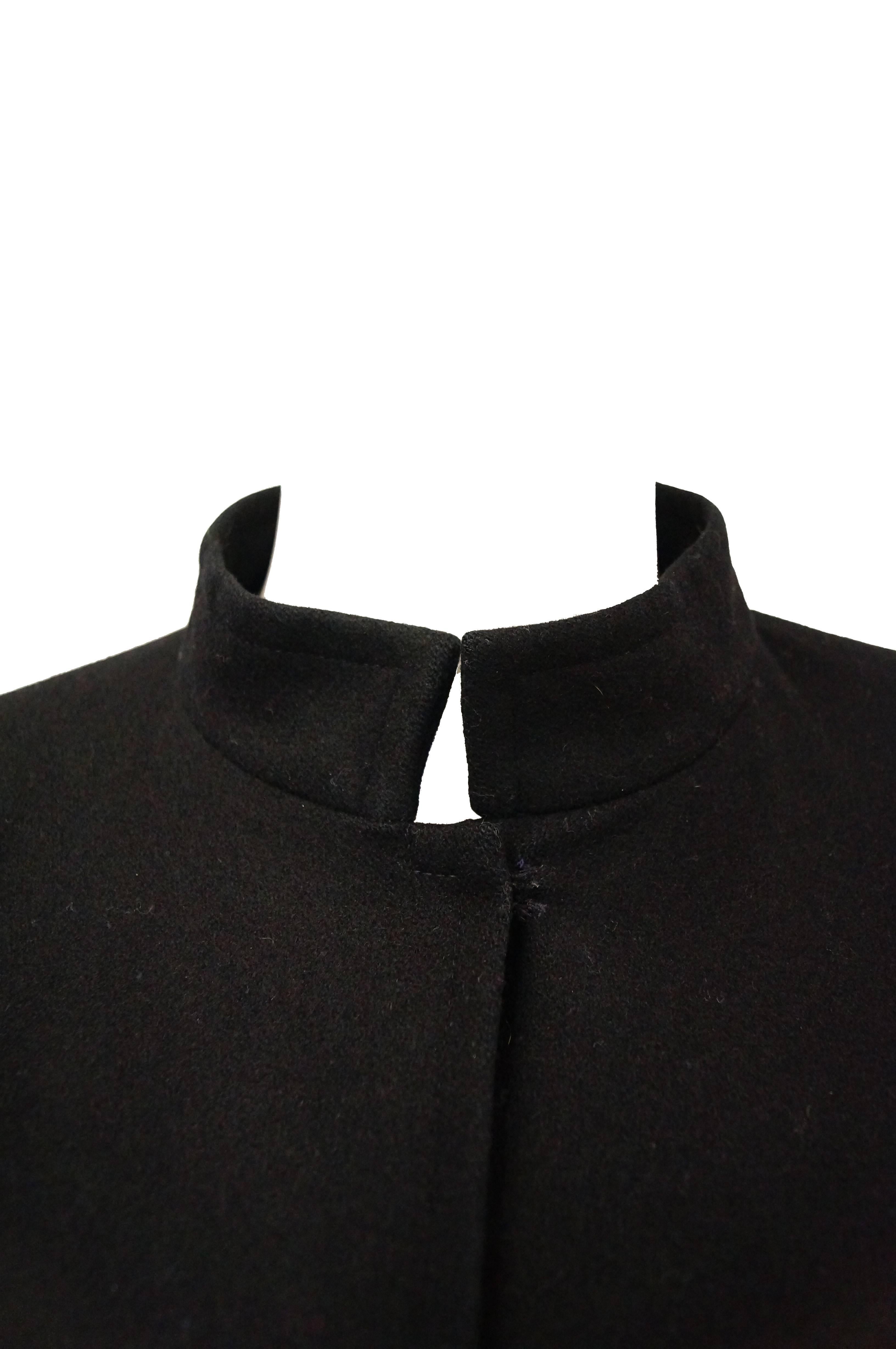 This iconic black wool Yves Saint Laurent cape is mid-calf length and features snaps for closure on the neck. The cape consists of a generous amount of solid black couture raised twill weaved wool, allowing it to slowly and softly billow with