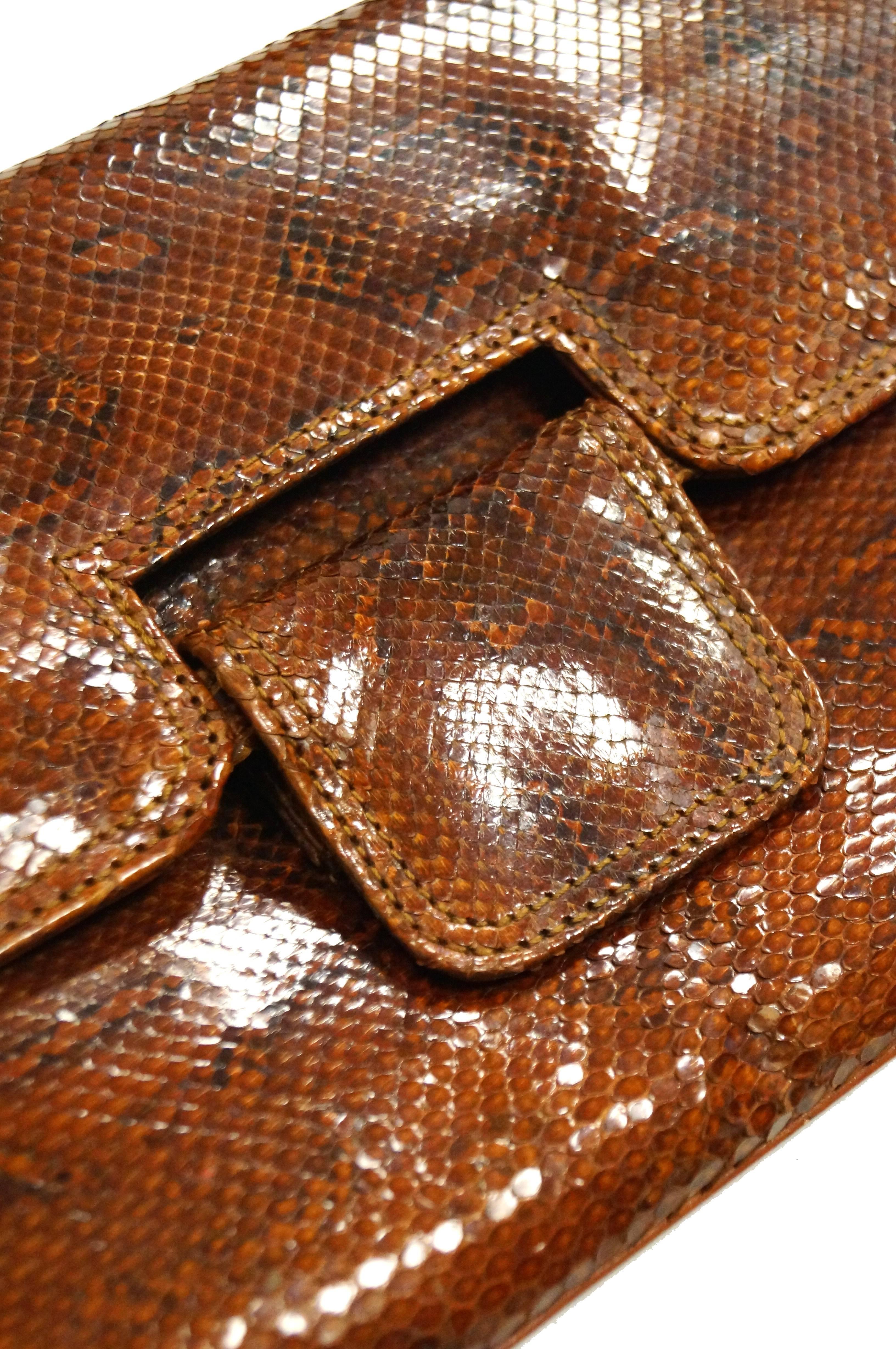 Gorgeous ochre - tone Argentine python snakeskin clutch by Rosenfeld! The clutch is rectangular, with clean lines and a glossy finish, as well as a fold-over closure. The interior is lined in tan leather, has a pocket, and features the Rosenfeld