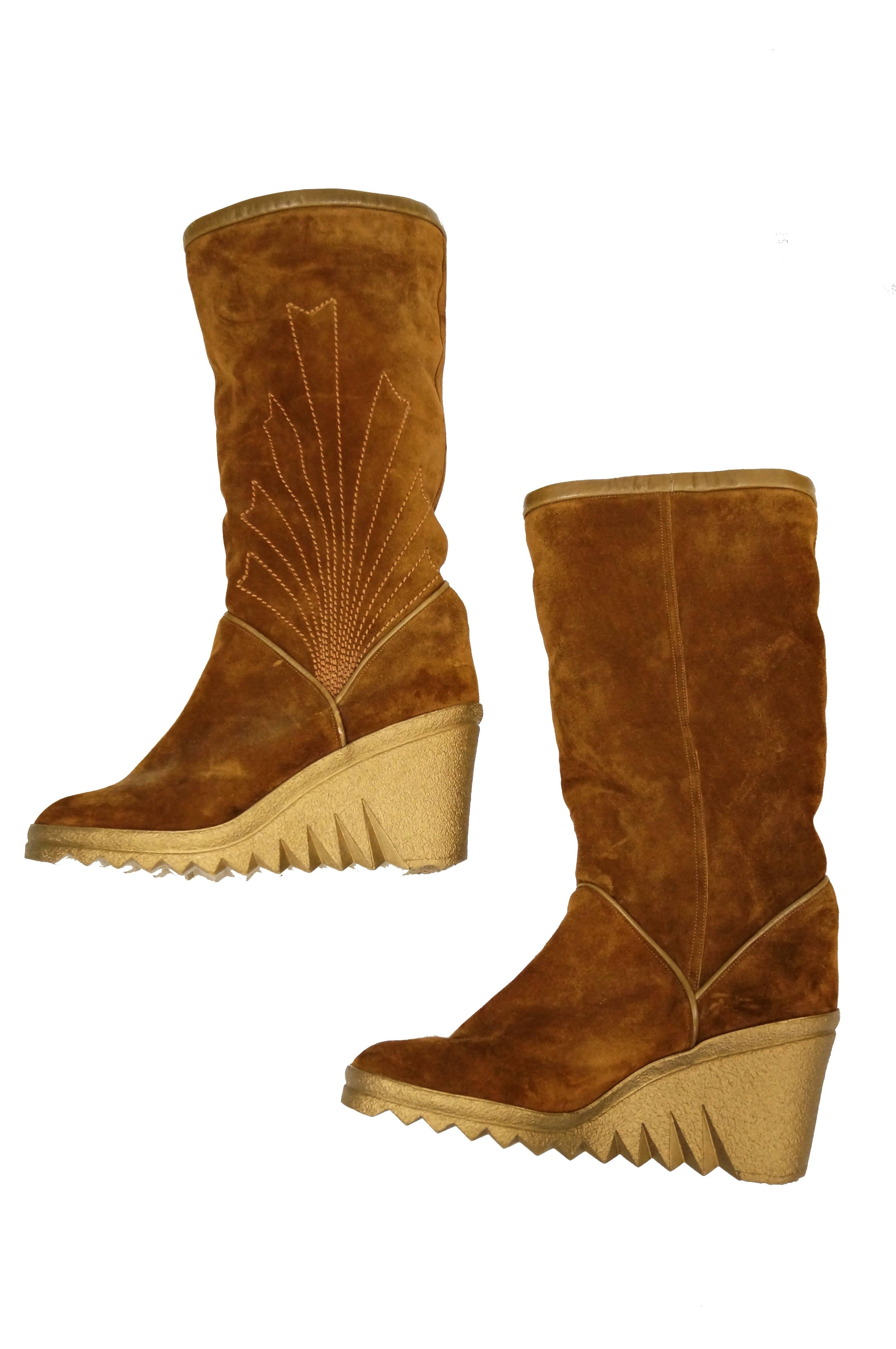 Wedge boots by Charles Jourdan featuring chestnut brown suede and natural rubber heels. The boots have a tall zig - zag tread, olive brown trim at the top, and a wonderful sunrise - like stitch detail on the outer panels. Climb a mountain - or climb