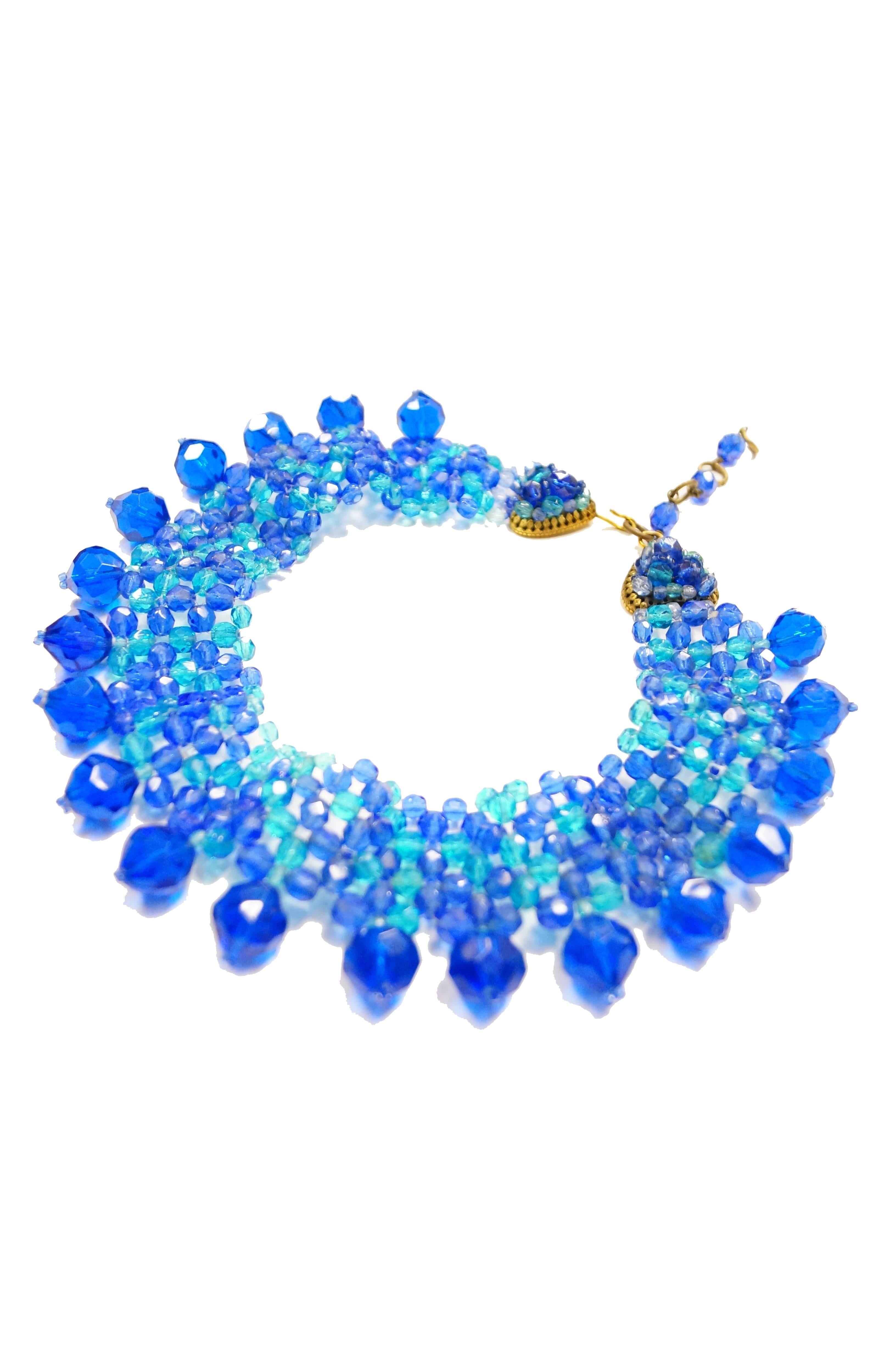 This gorgeous demi parure by Coppola e Toppo features a matching necklace and earrings. The necklace is composed of multiple rows of crystal royal blue and sky blue beads woven together into a thick collar - like choker necklace. The necklace has