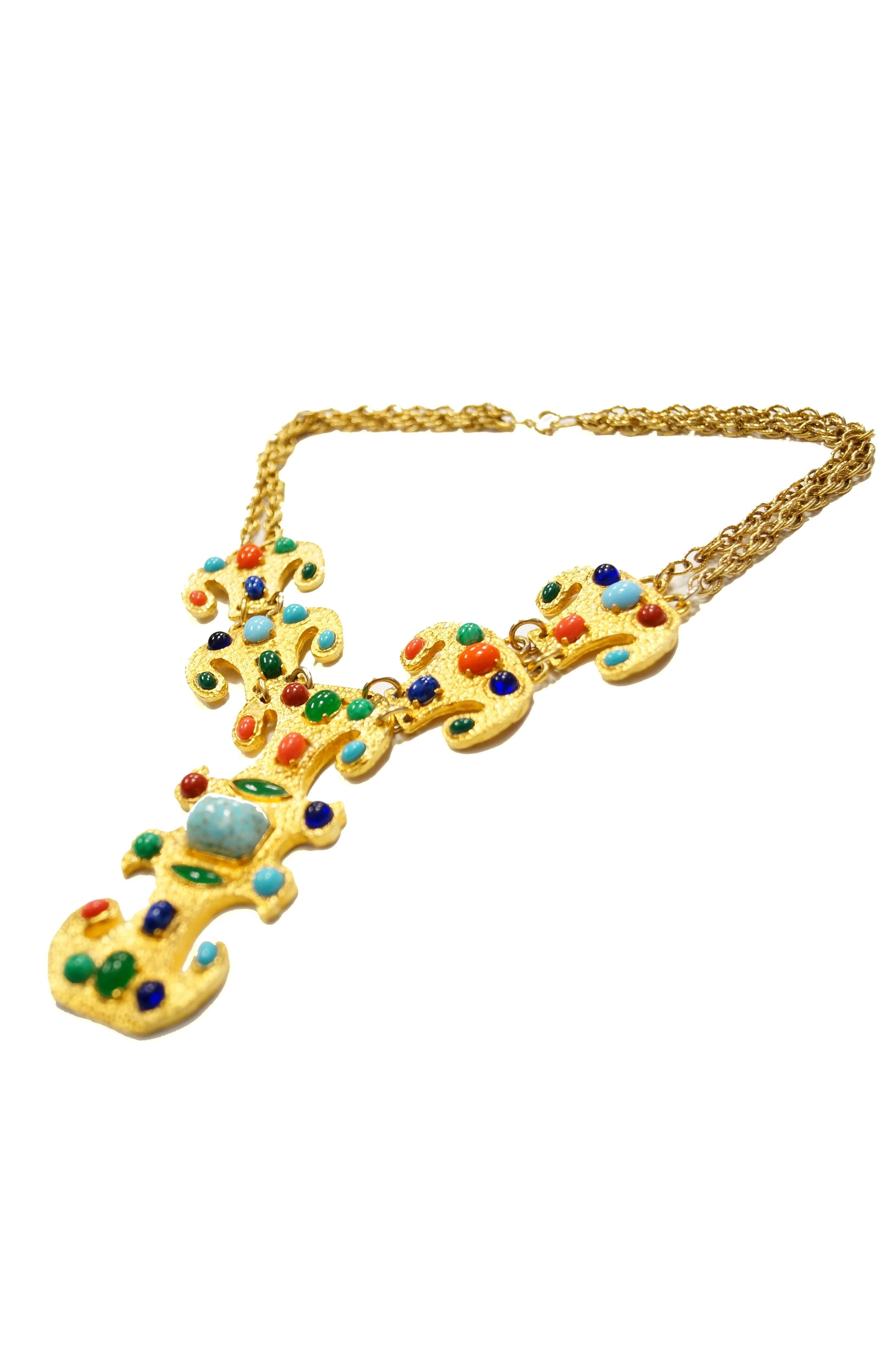 Fantastic gold - tone statement necklace by Donald Stannard! The necklace is composed of several heavy linked plates ornamented with bright and cheery cabochons! The central plate is key - like, with several notches and divots. 

The piece, with its