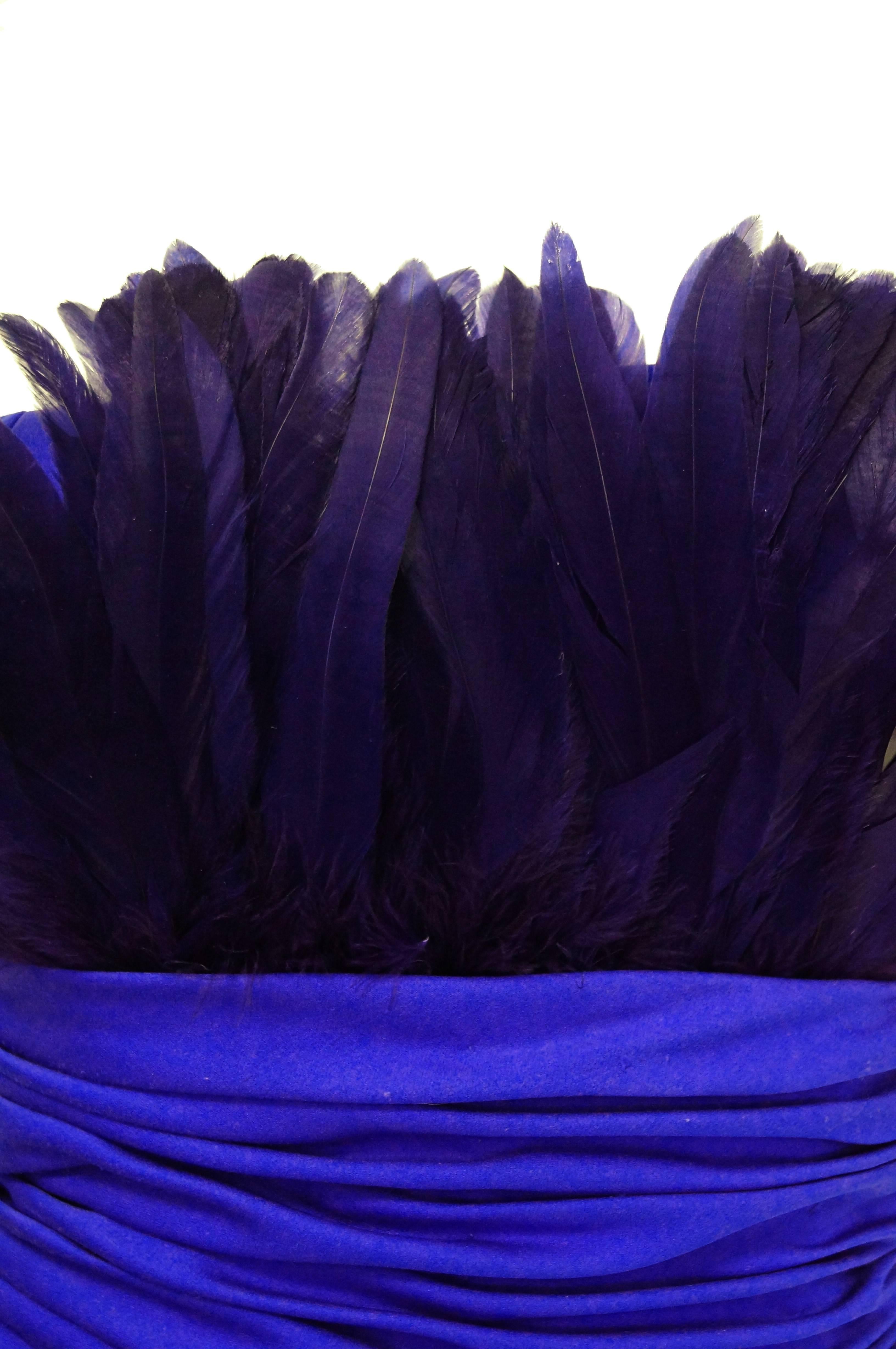Show stopping elegantly done strapless cocktail dress by Victor Costa. Ultramarine feathers cup the bust of this dress adding drama. The waist is ruched and the skirt is like an upside down tulip with an opening on the left side. Dress zips up the