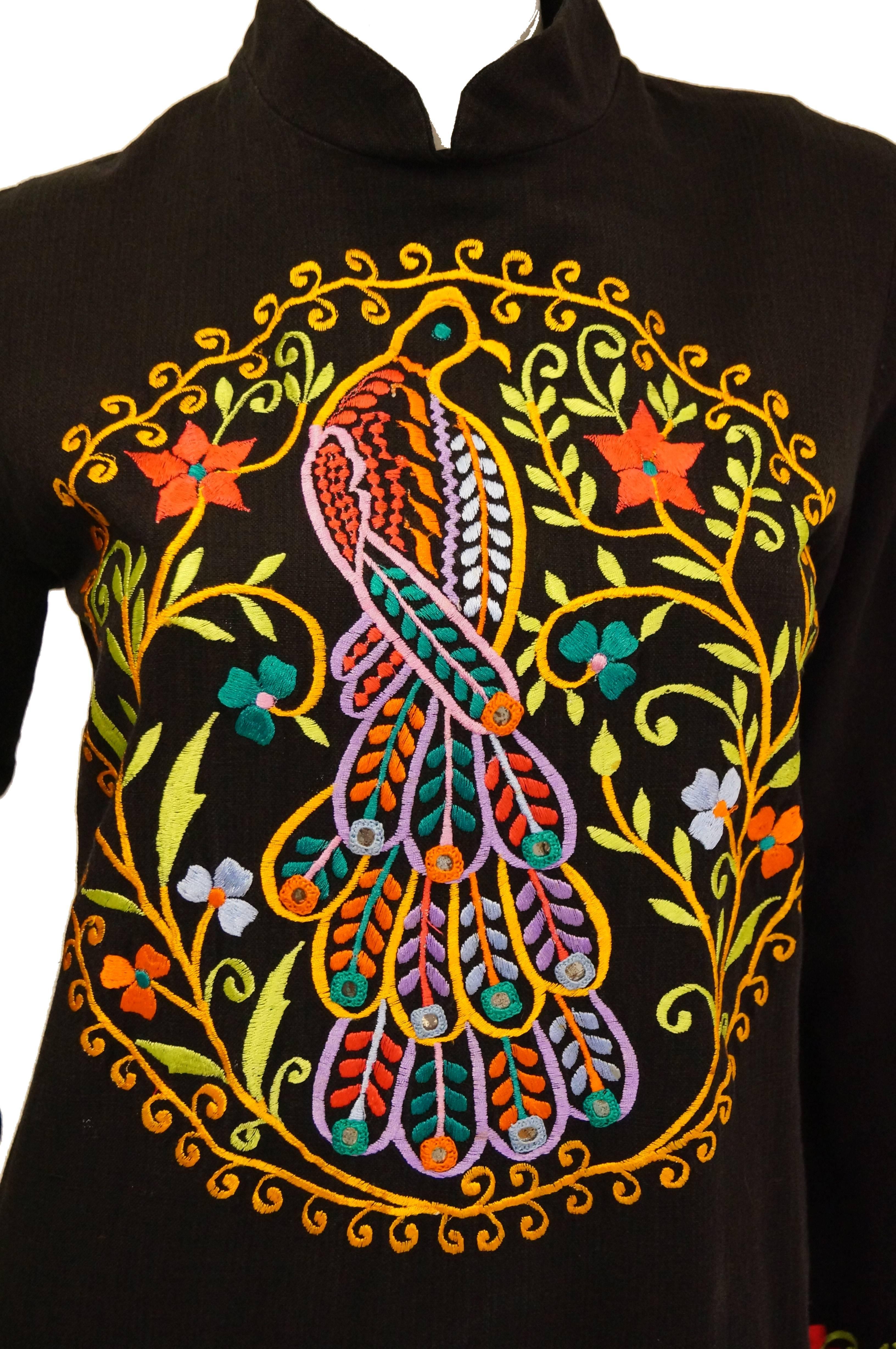 Fabulous colorful peacock embroidered caftan / kaftan by Ramona Rull! The 100% cotton caftan features a high mandarin collar, long sleeves with a slight flare, and has knee-length slits on both legs. The dress is embroidered in a multitude of colors